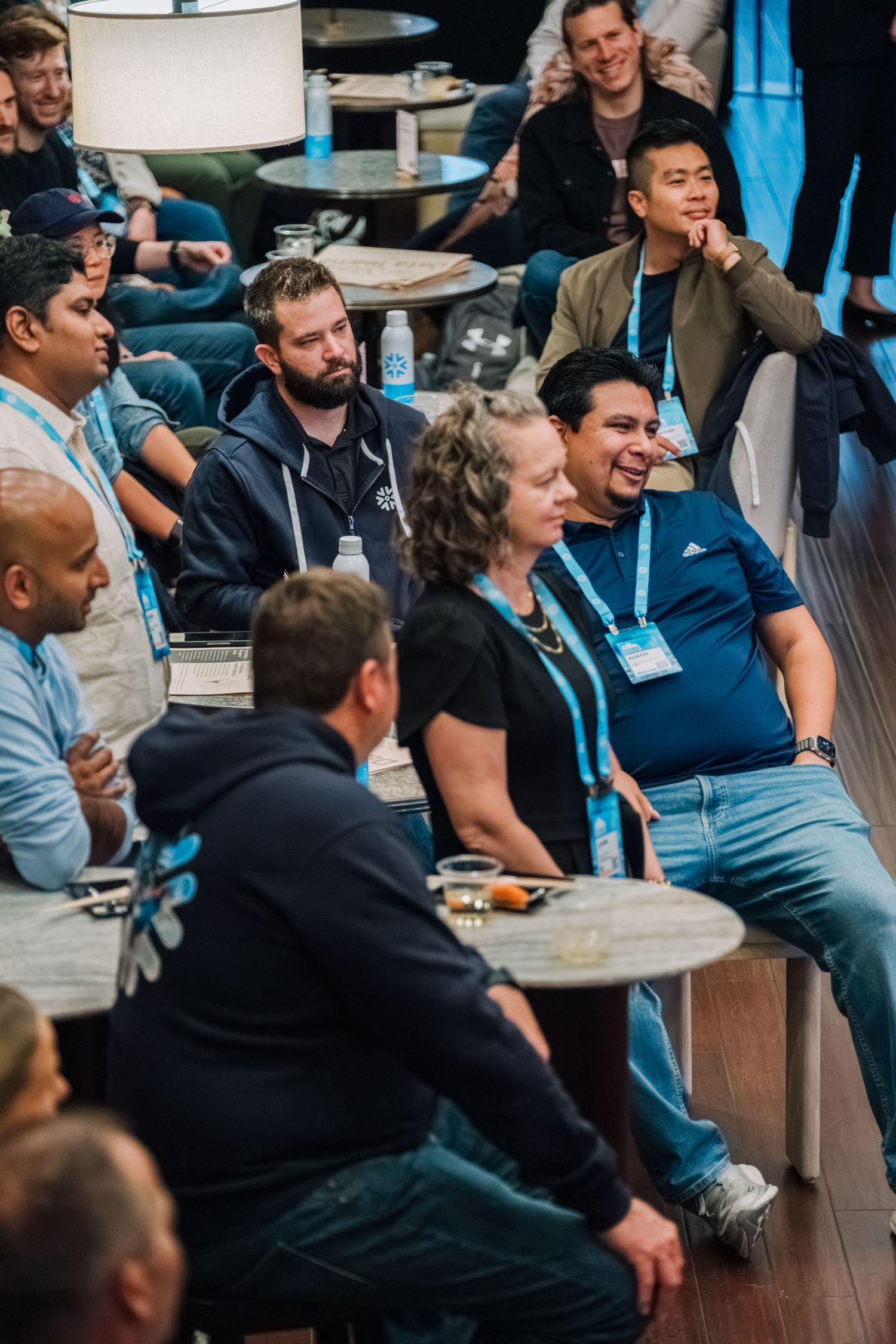 A diverse group of attendees laugh together during a casual conference or meetup event.