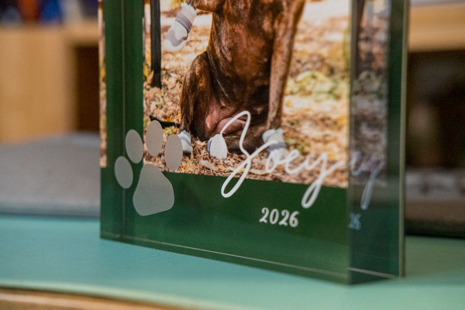 A green glass photo frame with decorative elements sits on display, showing a reflective surface.