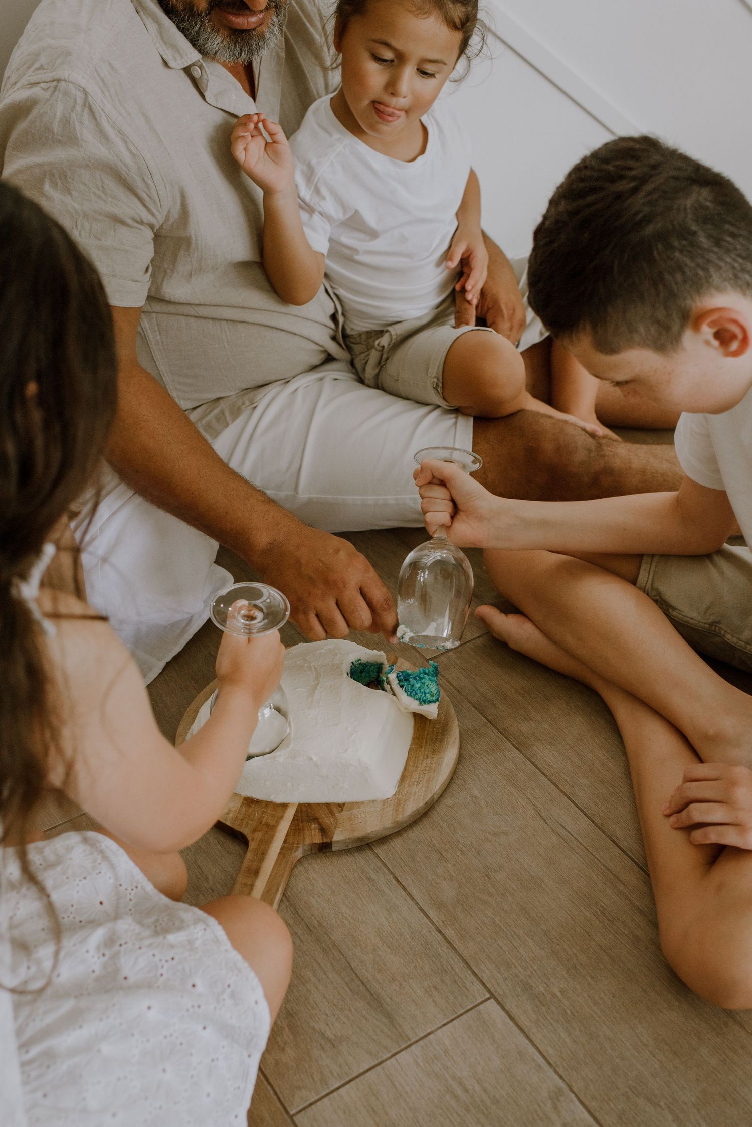 Family sitting together on floor playing with clear glass jars and writing materials in minimalist setting.