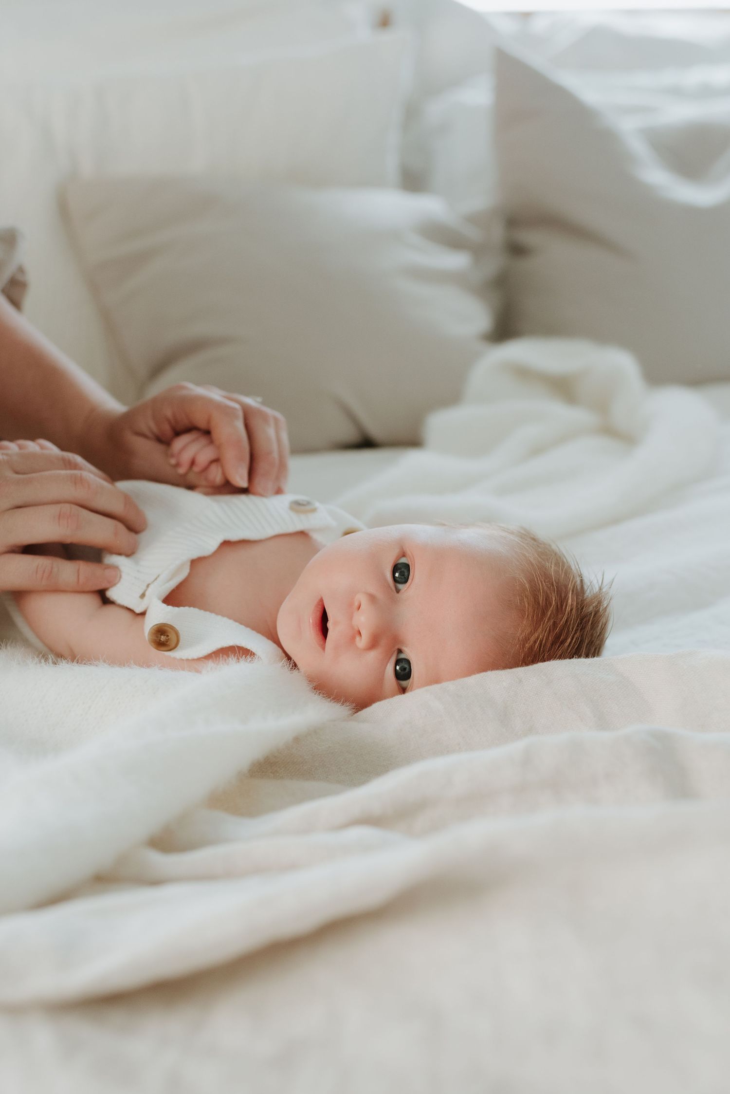 A sleeping baby lies on soft white bedding in a calming and gentle environment.