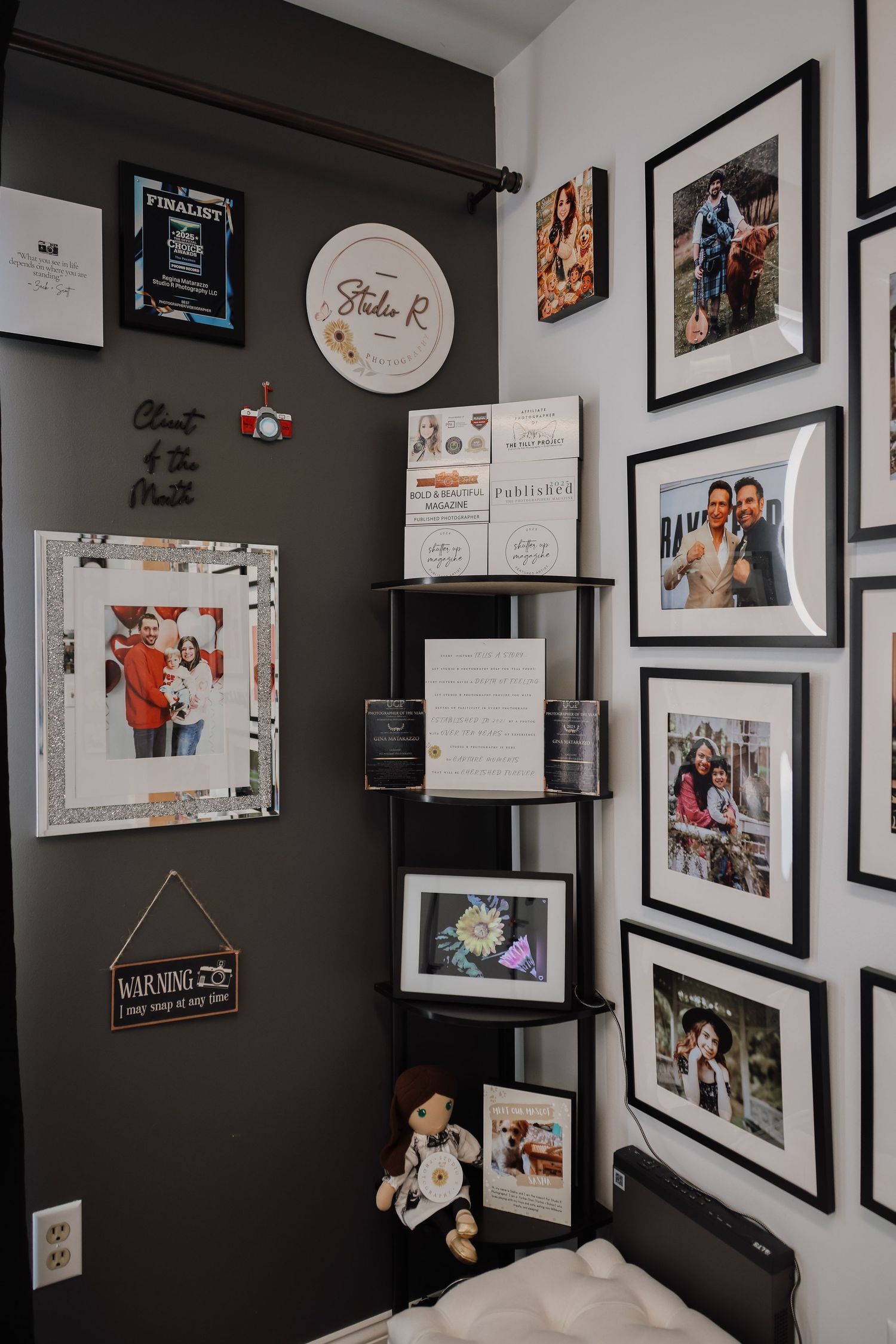 A gallery wall with framed photographs and artwork displayed against a dark painted wall in a modern interior space.