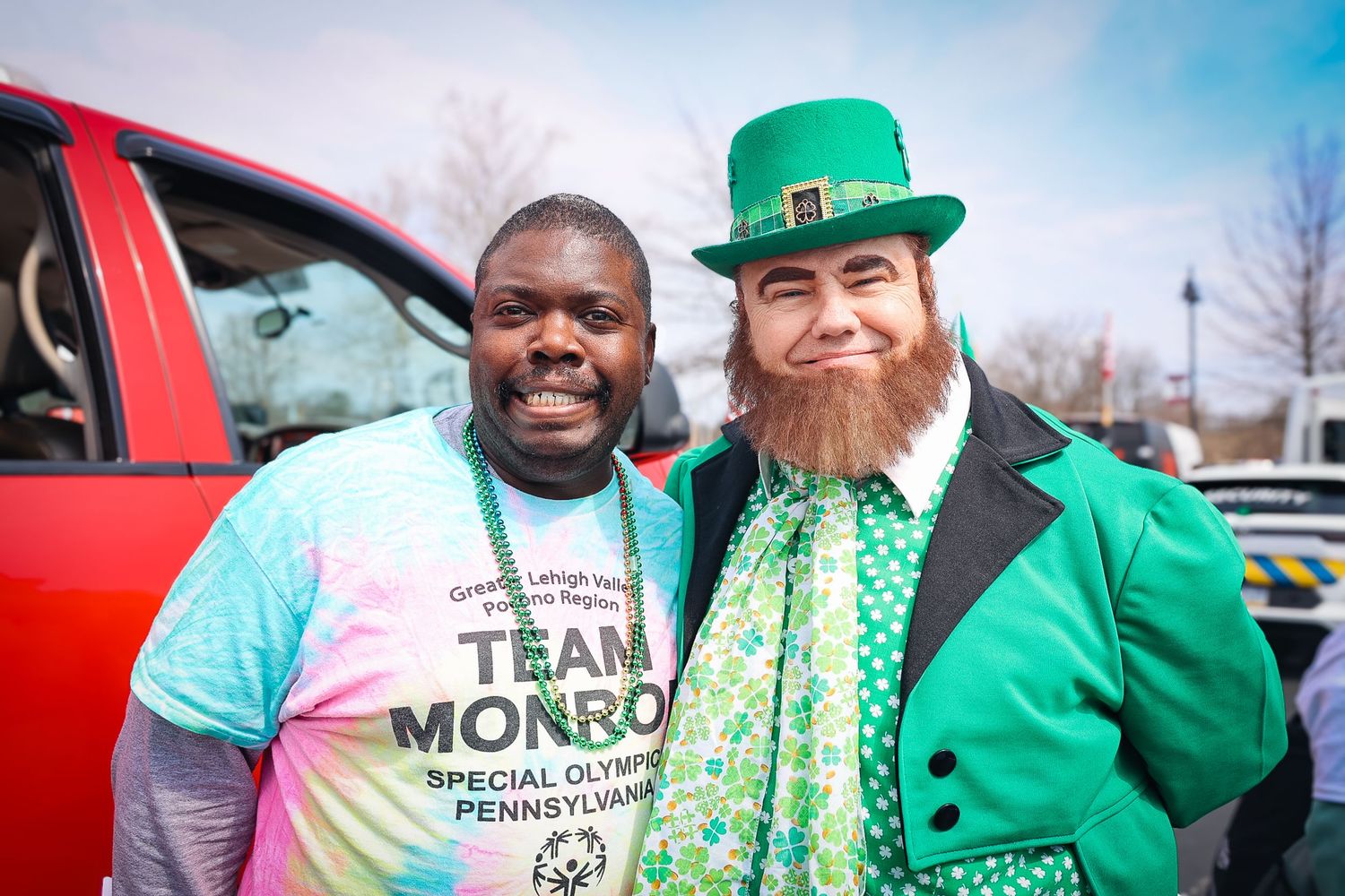 Two men pose together, one in a Team Monroe Special Olympics shirt, the other in a green leprechaun costume for St. Patrick's Day.