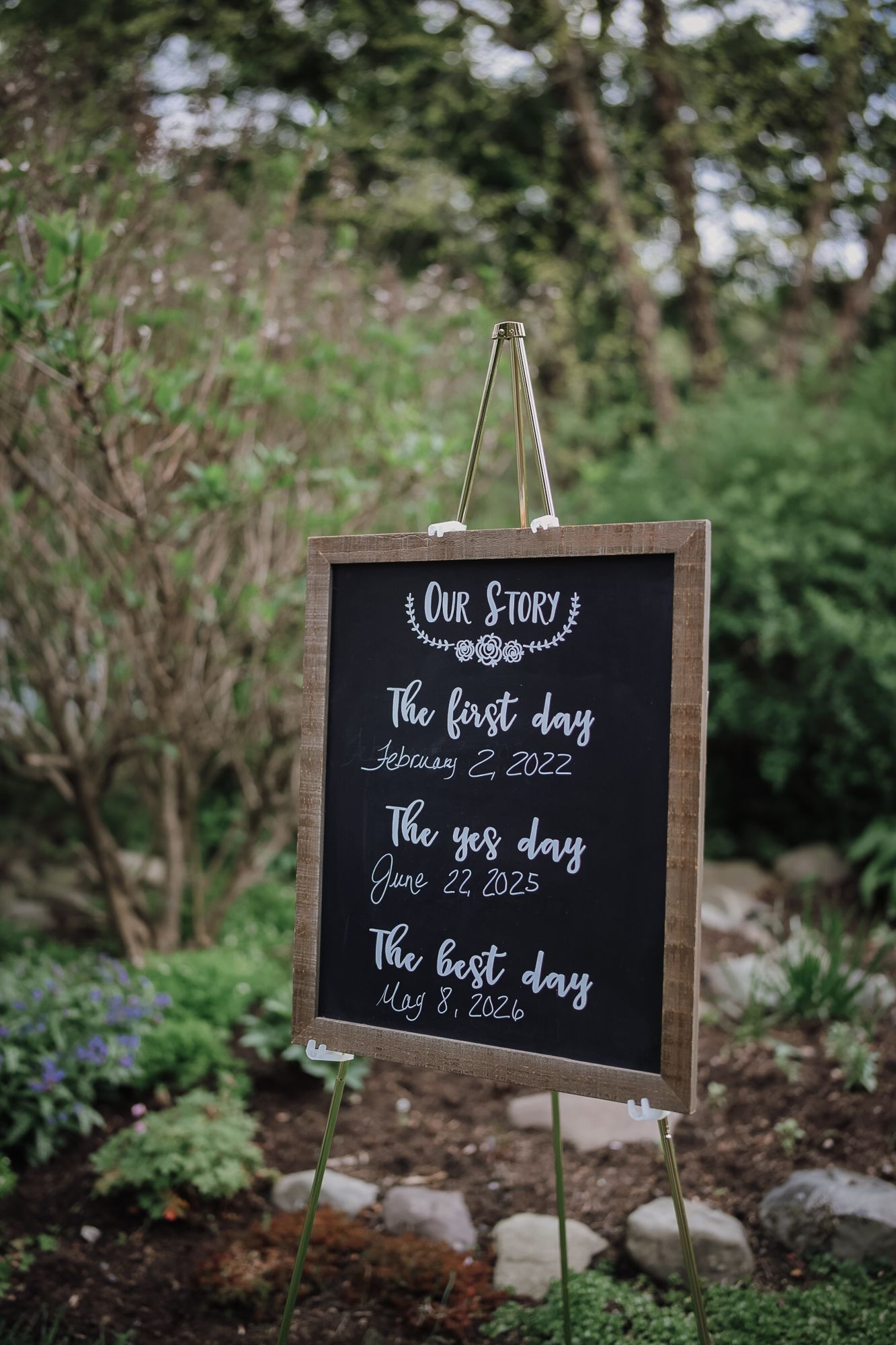 Chalkboard wedding sign on easel displaying Our Story with first date, engagement date, and wedding date.