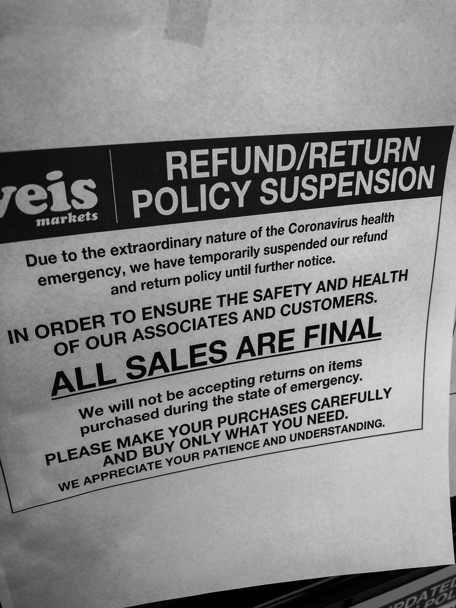 Store sign displaying refund and return policy suspension notice during Coronavirus health emergency with final sales policy.