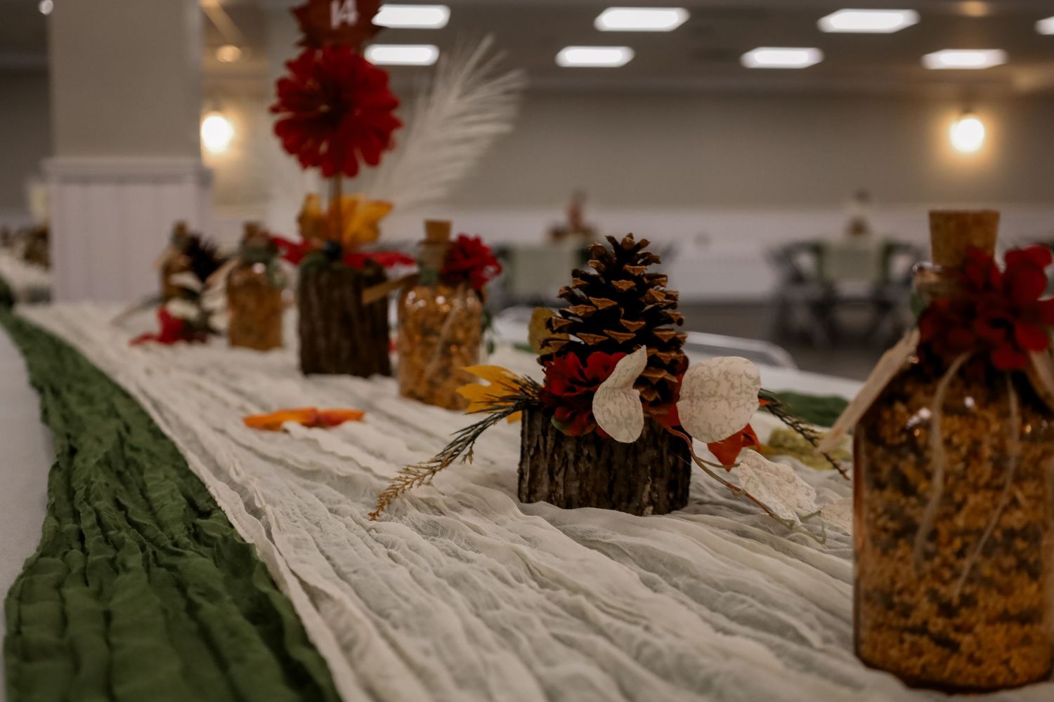 Rustic holiday table setting with pinecones, red berries, and white linens decorated for Christmas dinner.