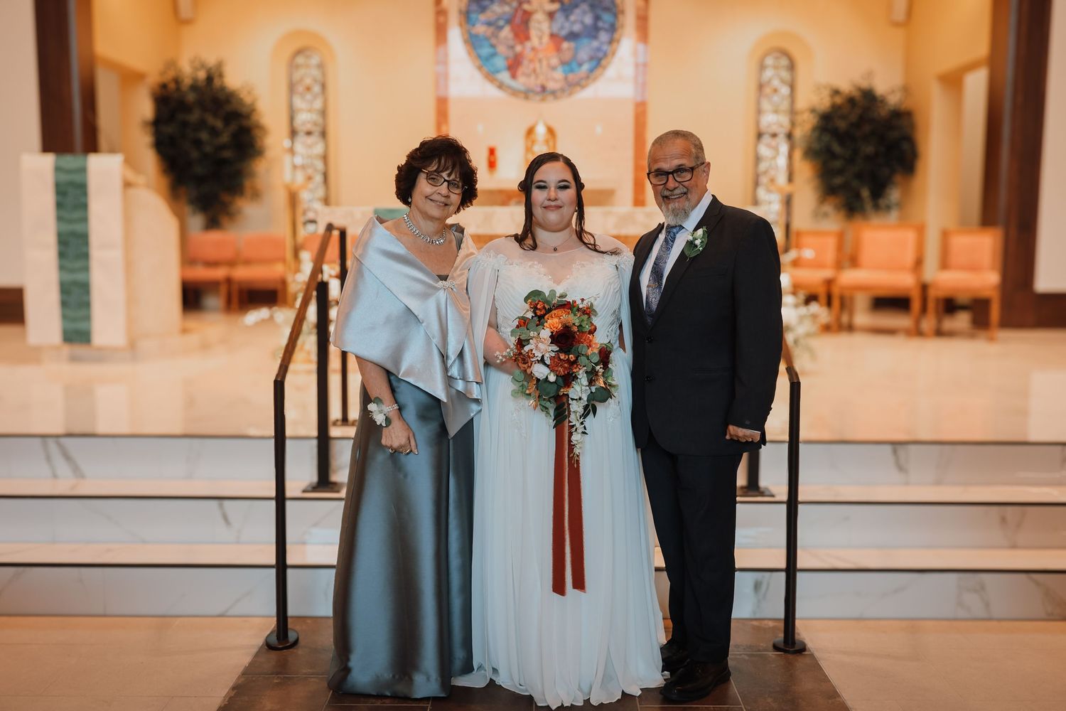 A couple stands at a church altar during a wedding ceremony with elegant floral decorations and warm lighting.