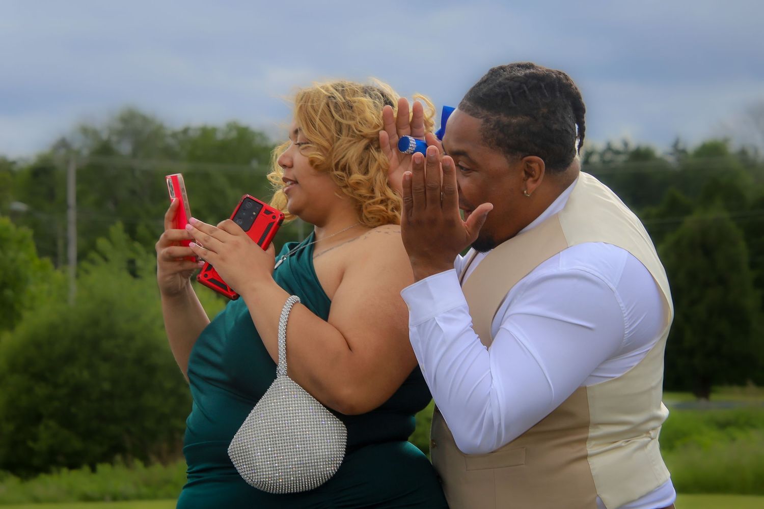 A couple embraces and dances together outdoors on a sunny day in a natural setting.