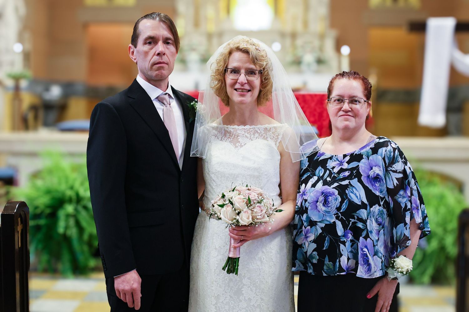 A group photo at a wedding ceremony with the wedding party posing together indoors.