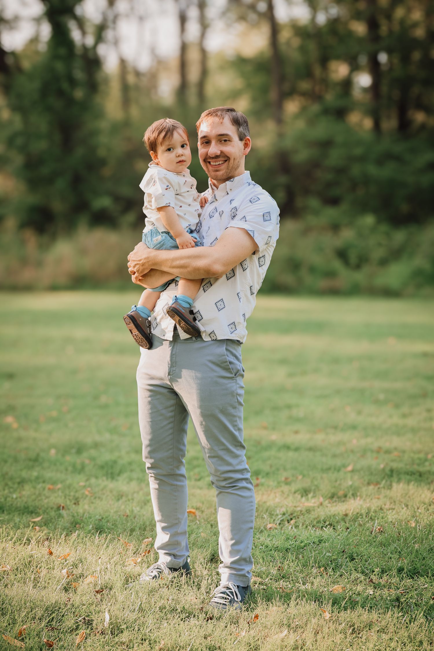 A heartwarming moment between parent and child playing together on a grassy field at sunset.