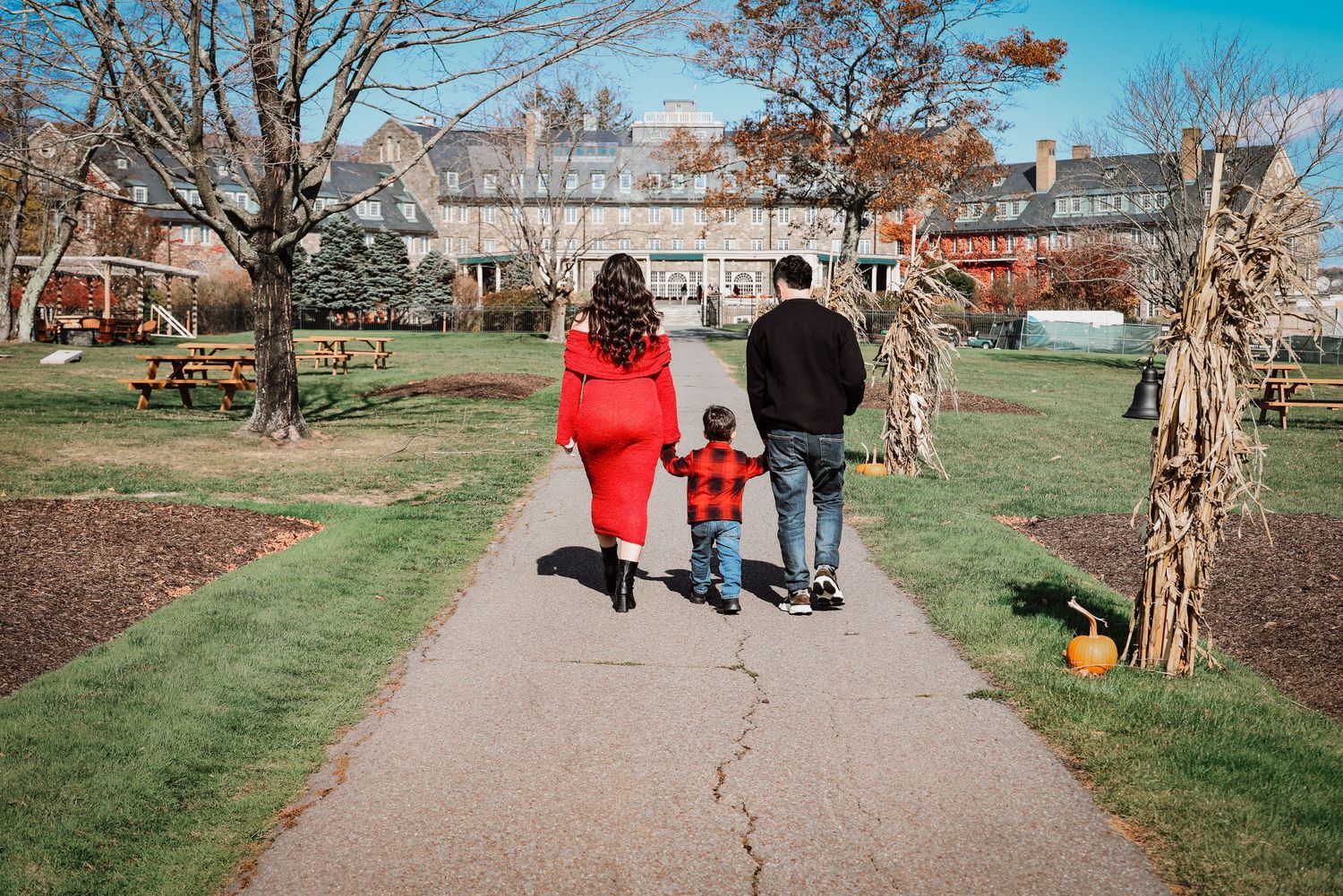 People walking along a path through a park on a sunny autumn day with bare trees lining the walkway.