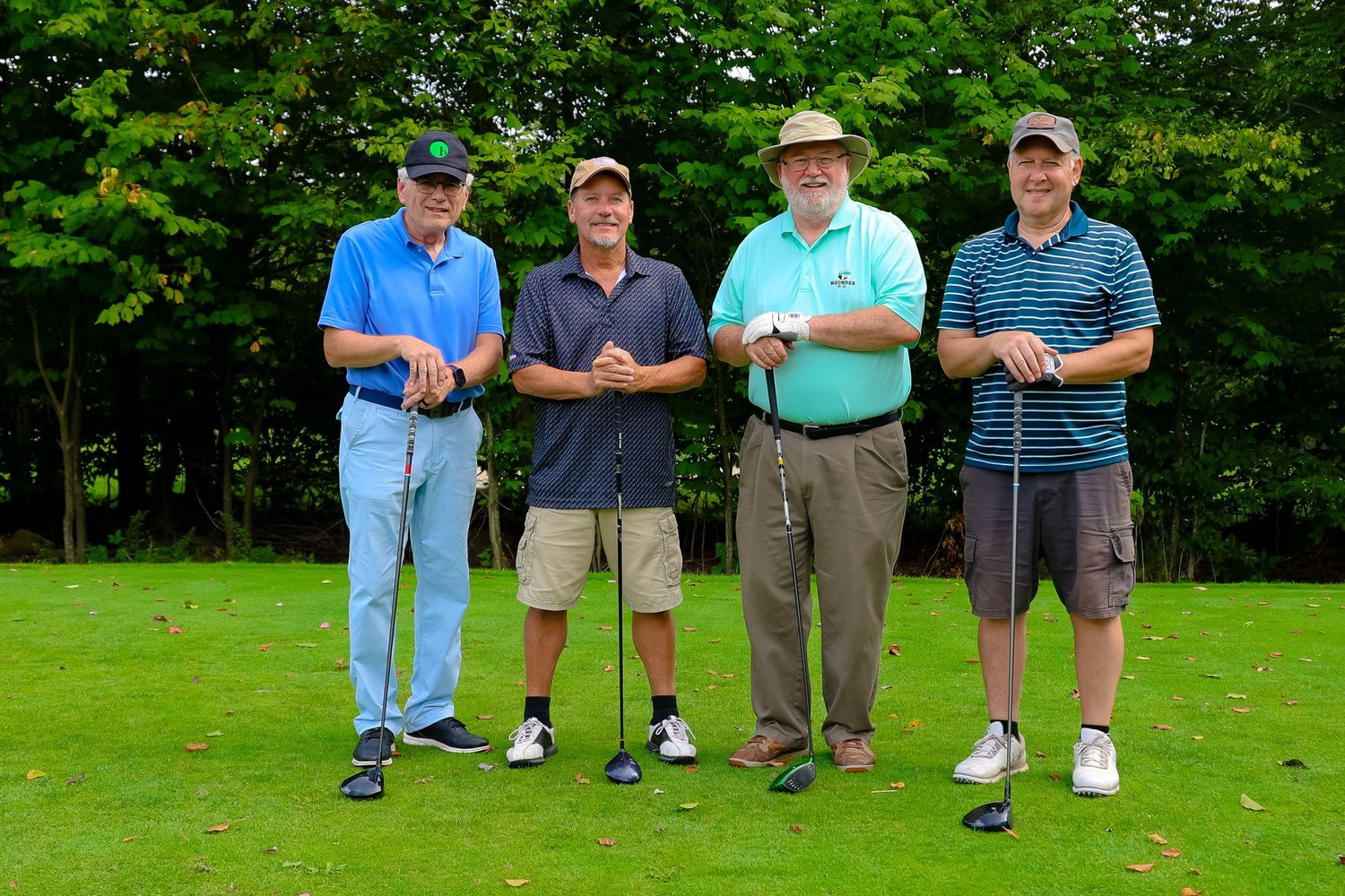 A group of golfers stand together on a lush green course during a summer day.