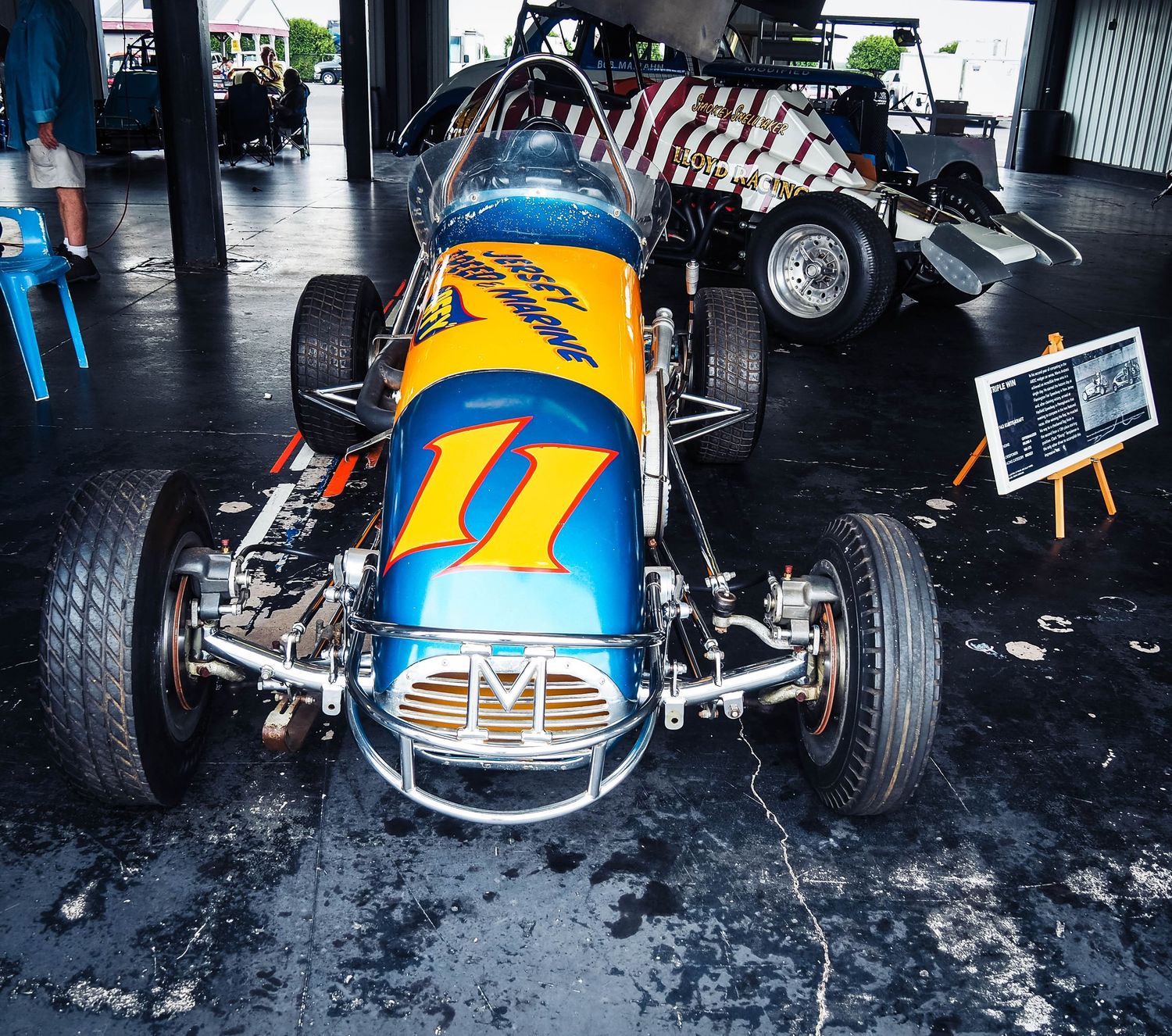 Vintage blue and yellow race cars lined up in a garage showing classic racing heritage and automotive history.