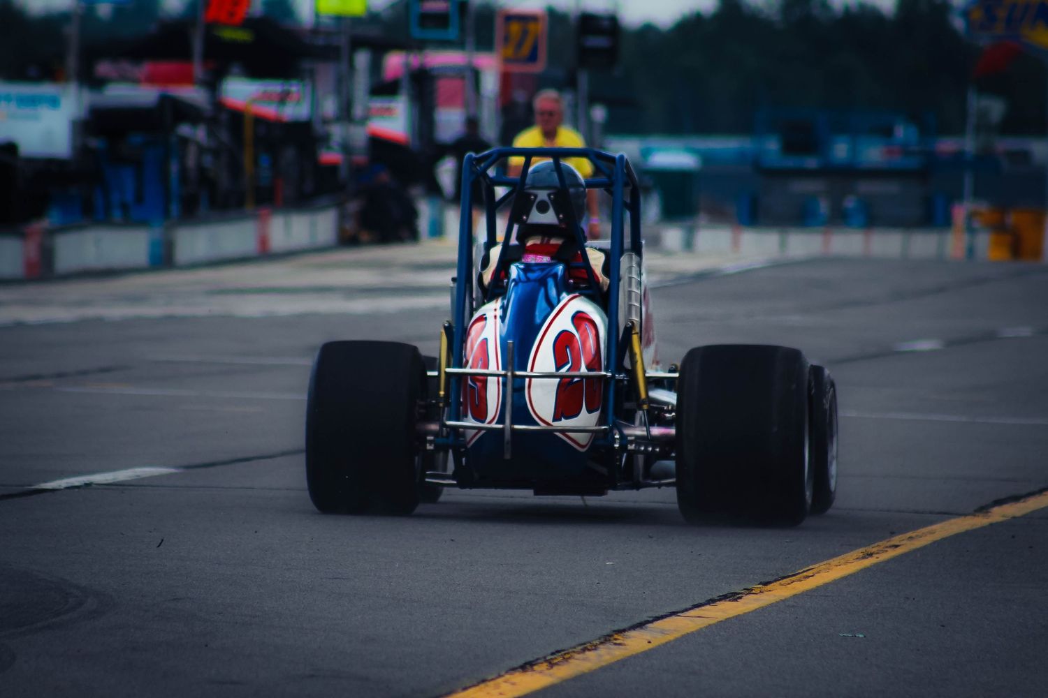 Formula racing car speeds down racetrack with orange and yellow sparks flying from underneath during competition.