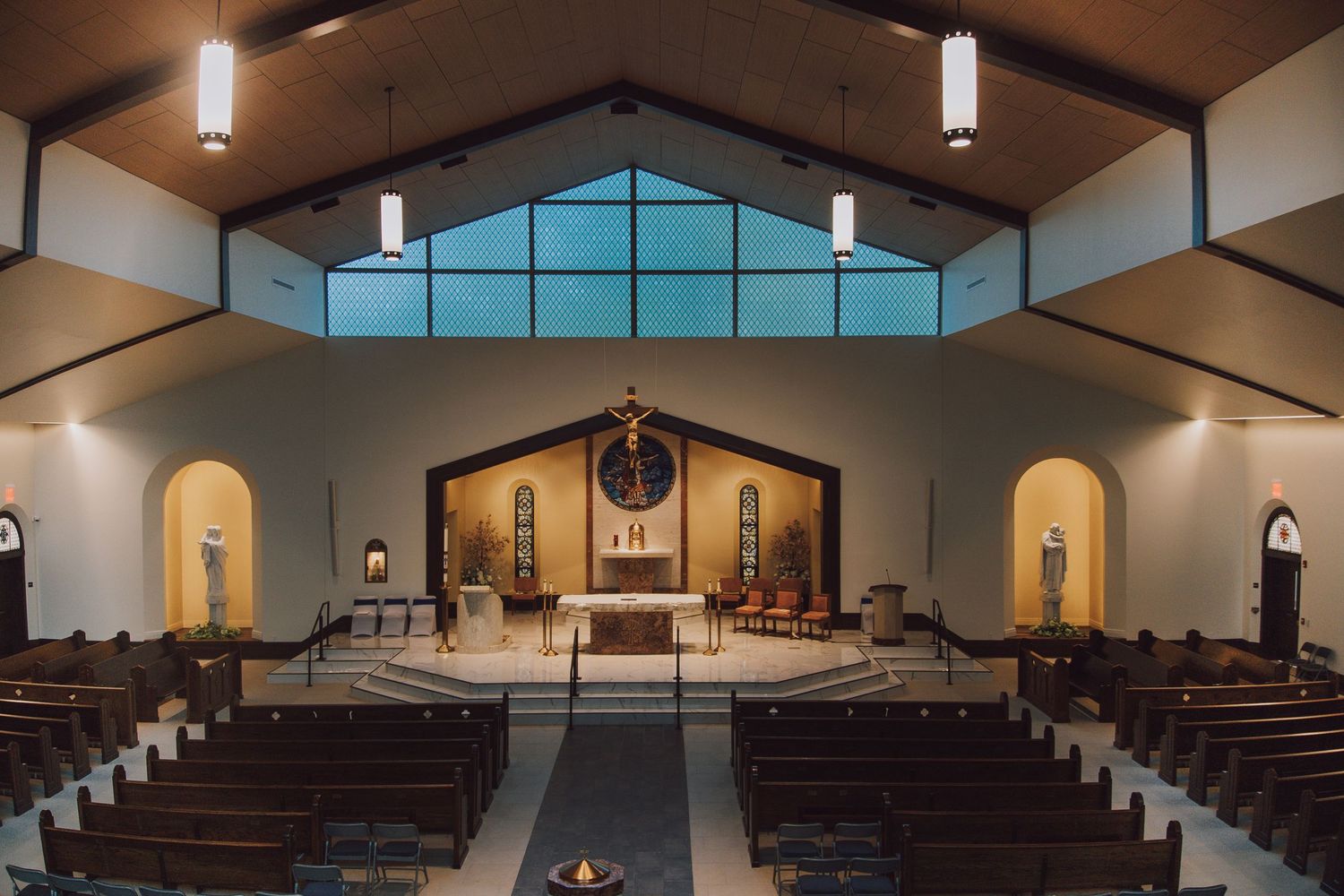 Interior view of a modern church sanctuary with wooden beams, pews and clerestory windows illuminating the space.