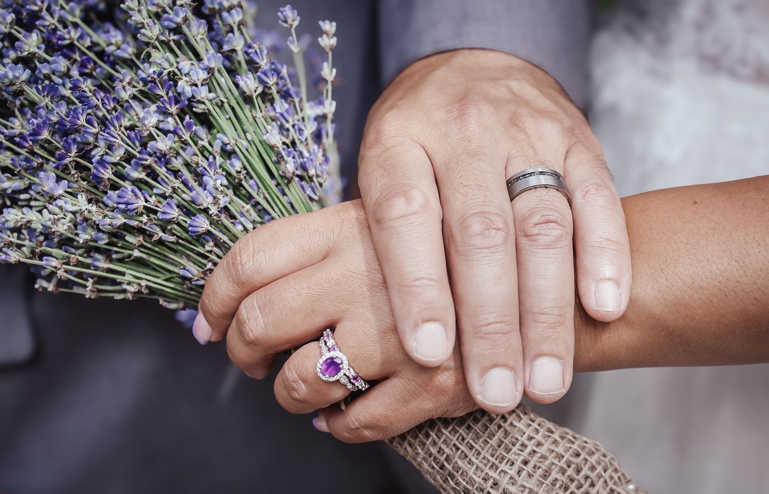 Detail shot of hands holding lavender sprigs showing wedding bands.