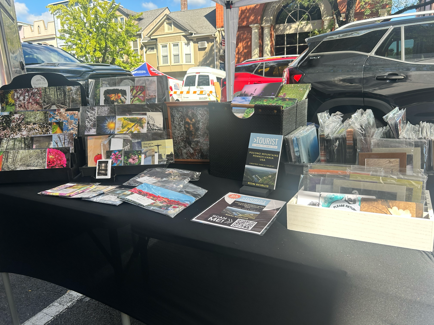 A vendor table displays various merchandise and printed materials at an outdoor market or street fair.