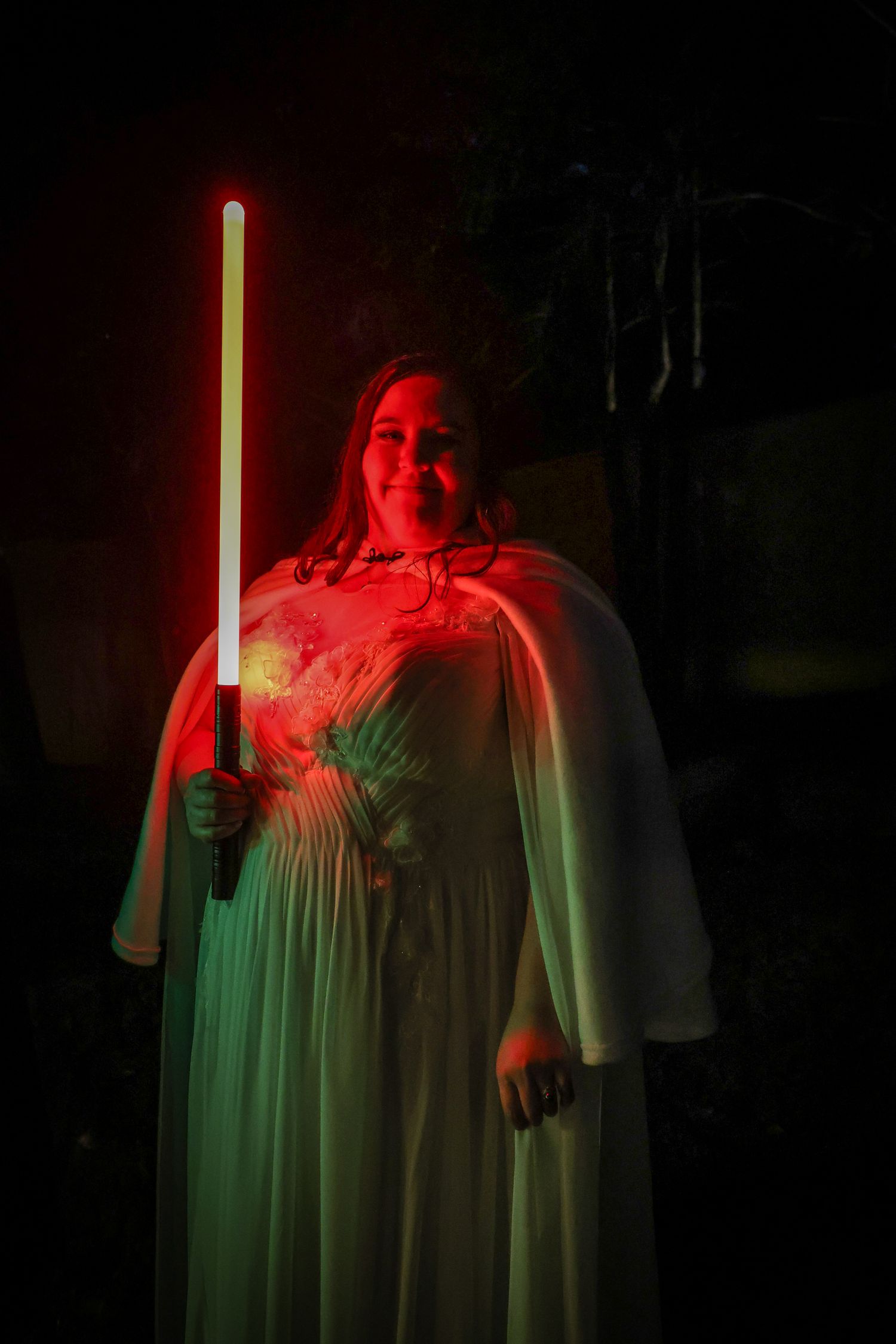 A figure in a flowing dress illuminated by dramatic red and green lighting creates an ethereal atmospheric effect.