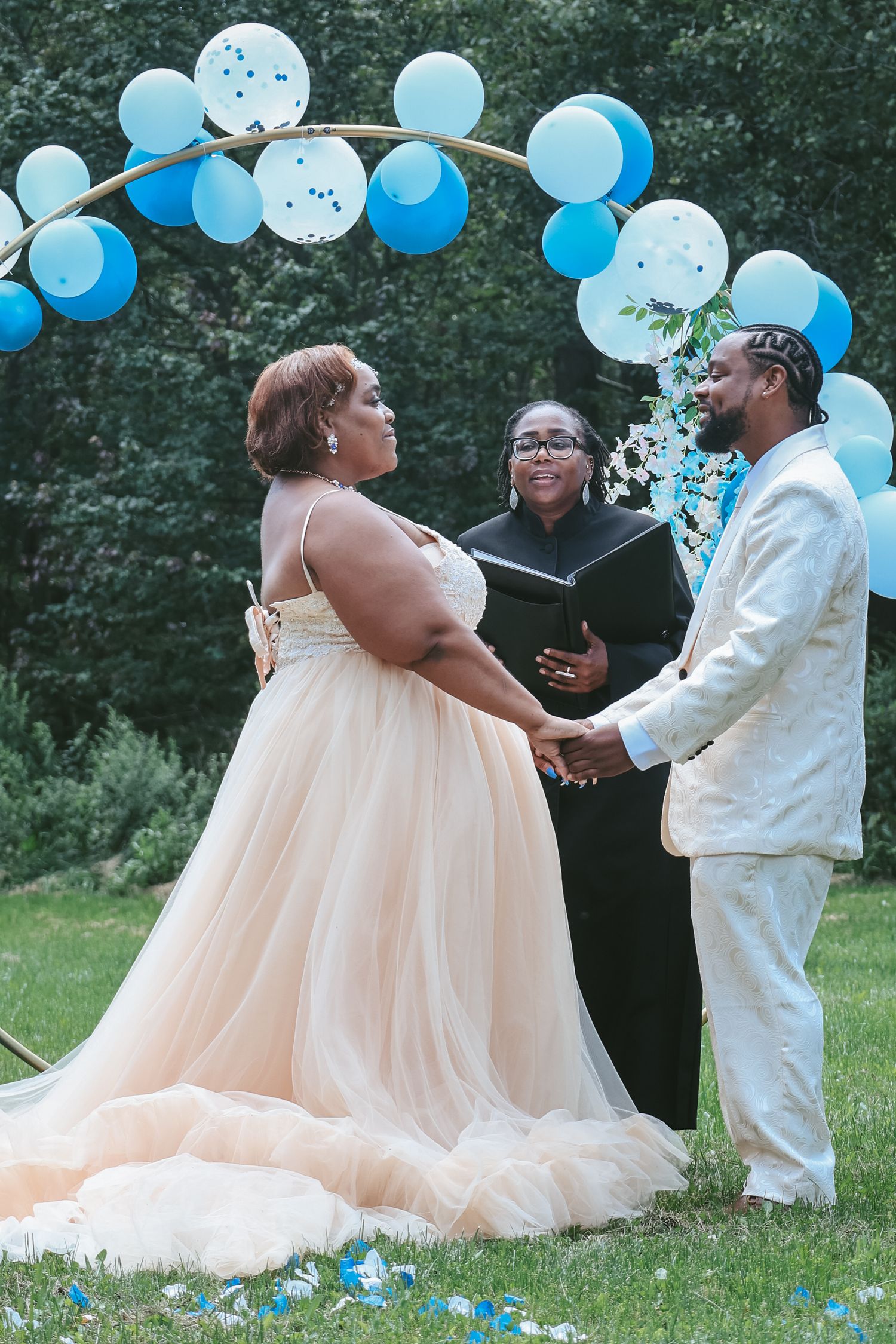 A couple celebrates their wedding day outdoors with blue balloons and a peach-colored gown in a romantic photo series.