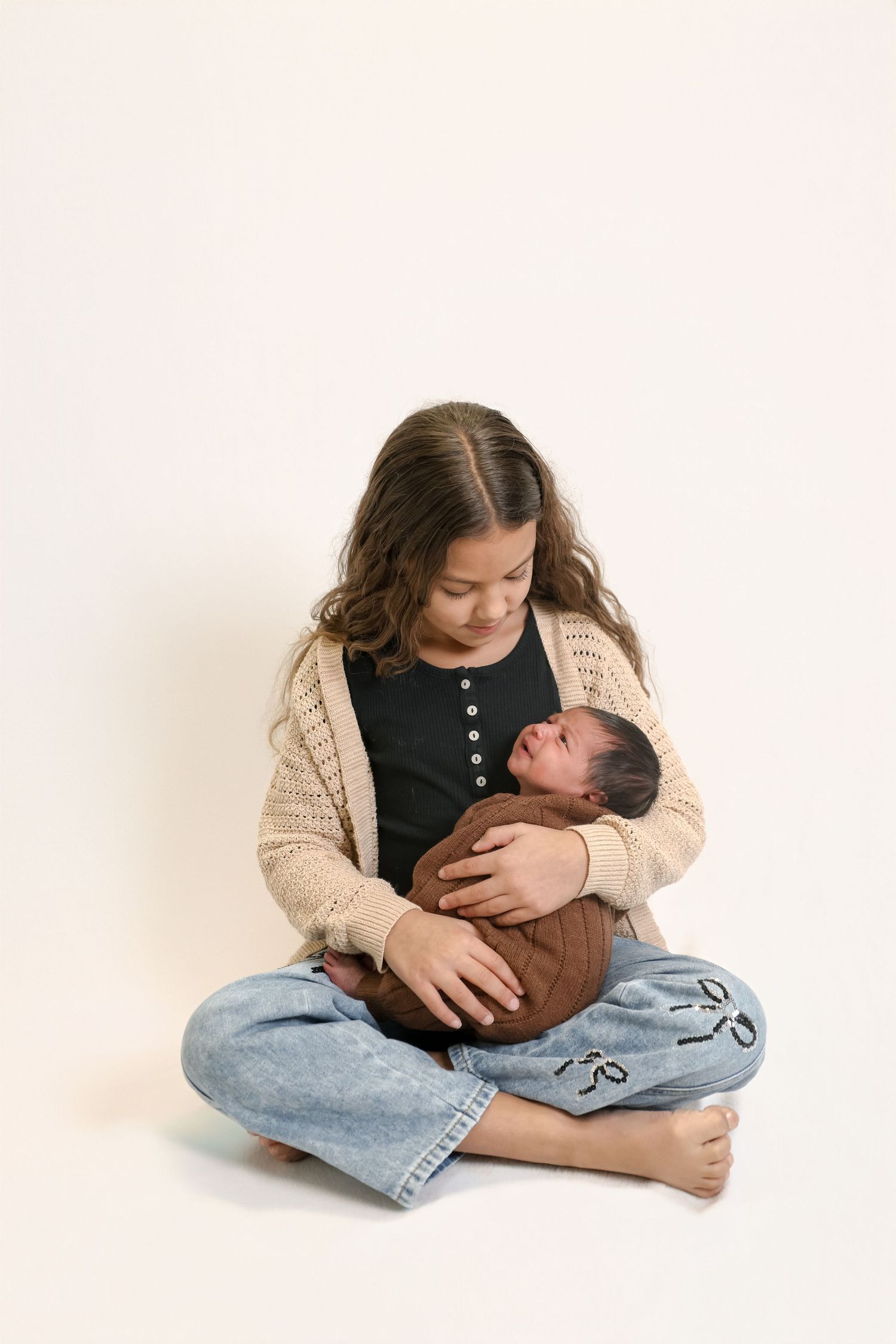A series of tender moments showing a parent cradling a sleeping infant while sitting on a white background.