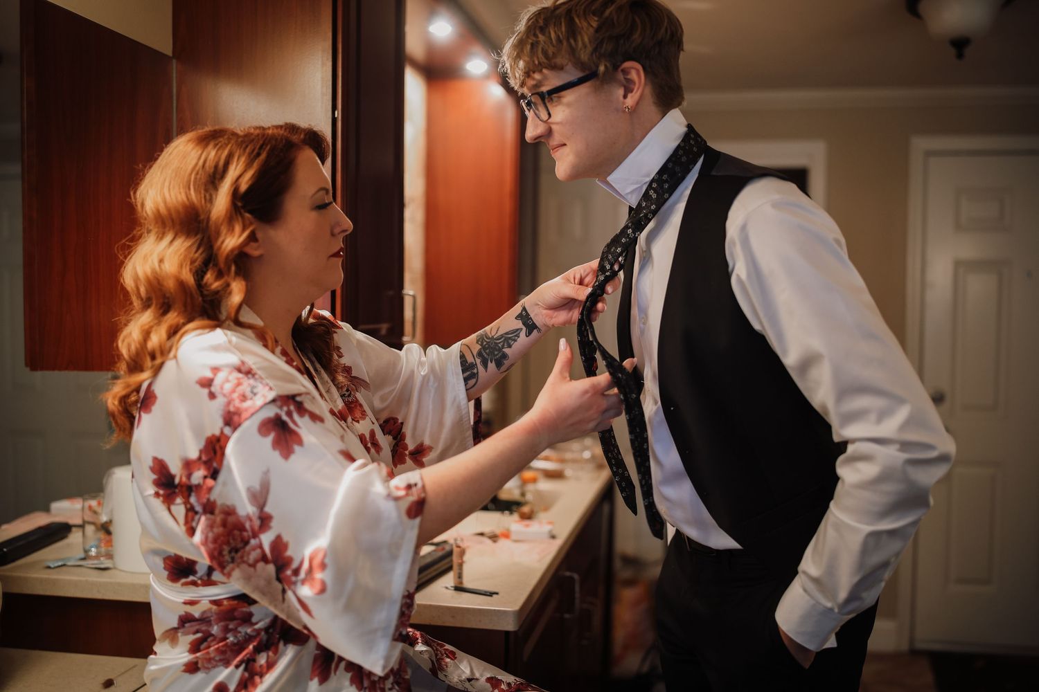 A couple in formal attire share an intimate dance moment in a warmly lit room.
