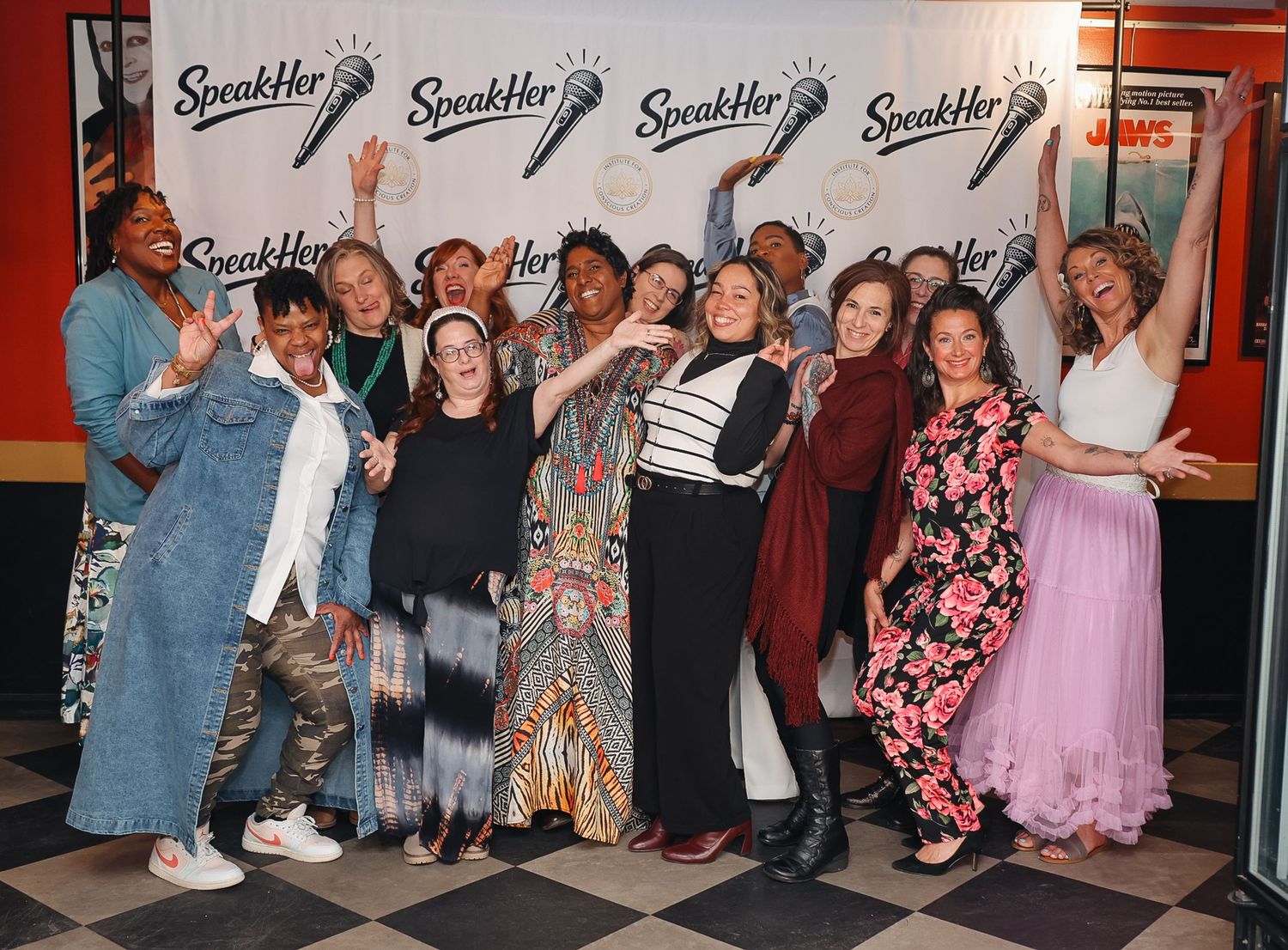 Group of women posing and celebrating at a SpeakHer event, smiling and raising their arms joyfully.