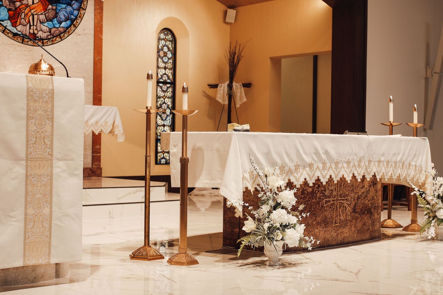 Interior view of a modern church sanctuary with cream walls, decorative columns and elegant lighting fixtures.