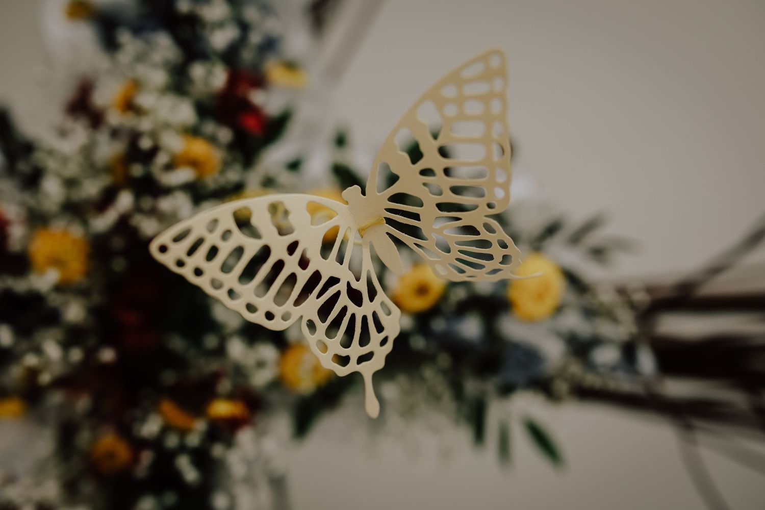 Wedding bouquet and decor featuring delicate white butterfly ornaments and yellow flowers arranged with greenery.