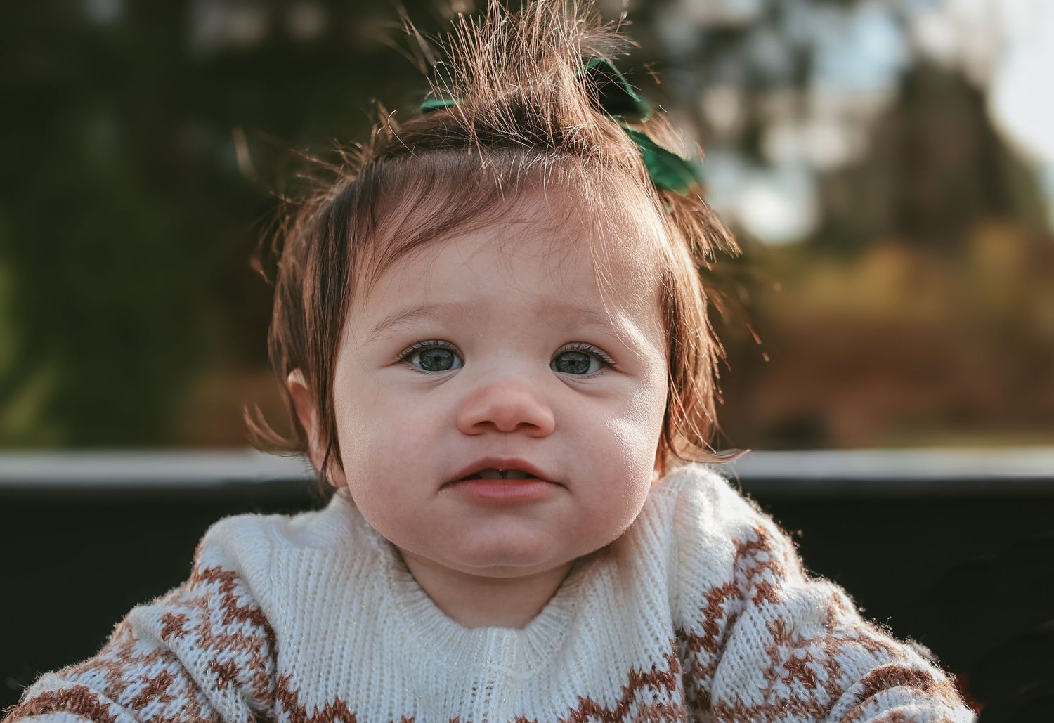 Close-up portrait of smiling baby in knit sweater with messy hair.