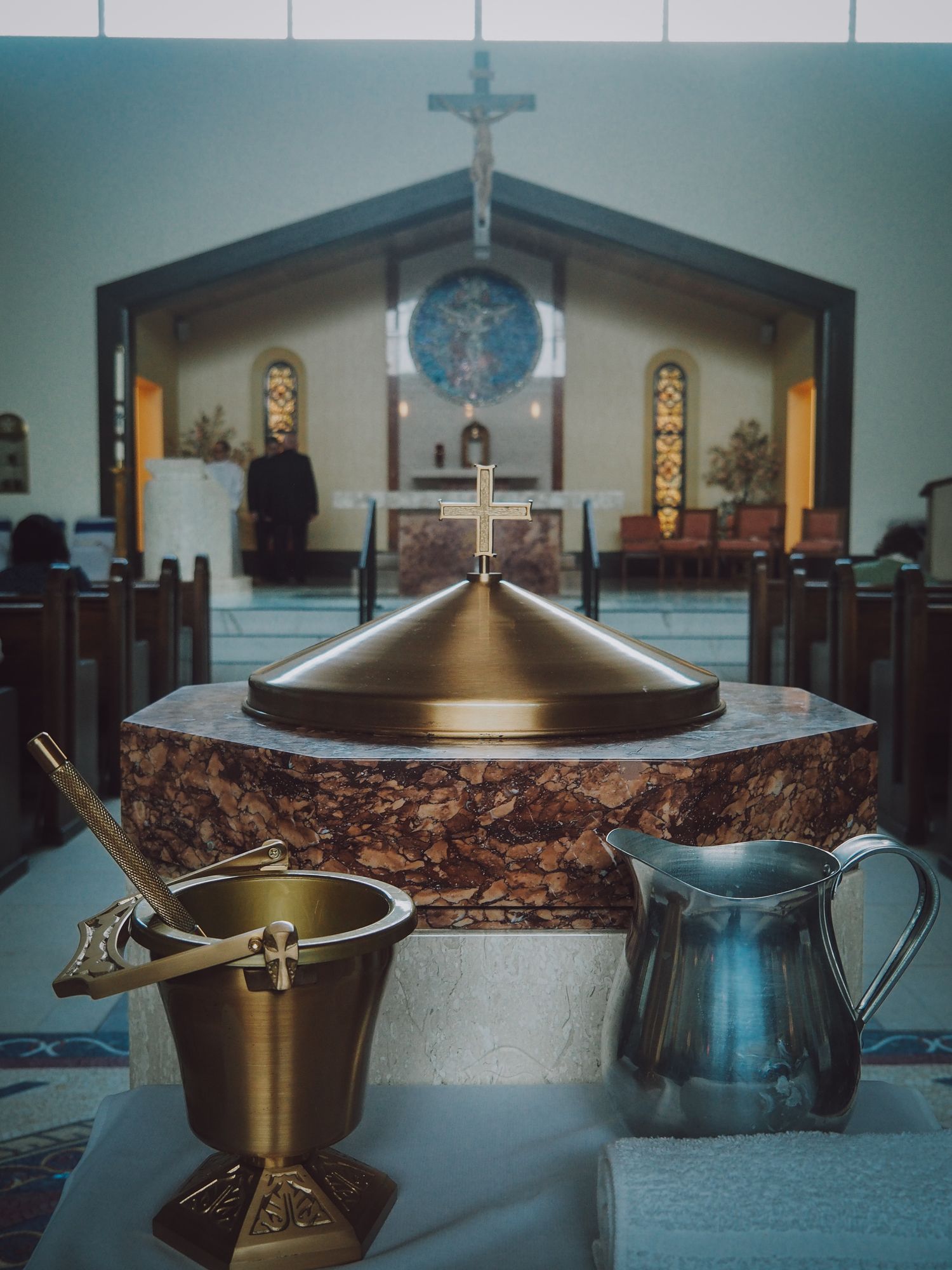 A series of brass communion chalices and plates arranged on an altar in a Catholic church sanctuary.