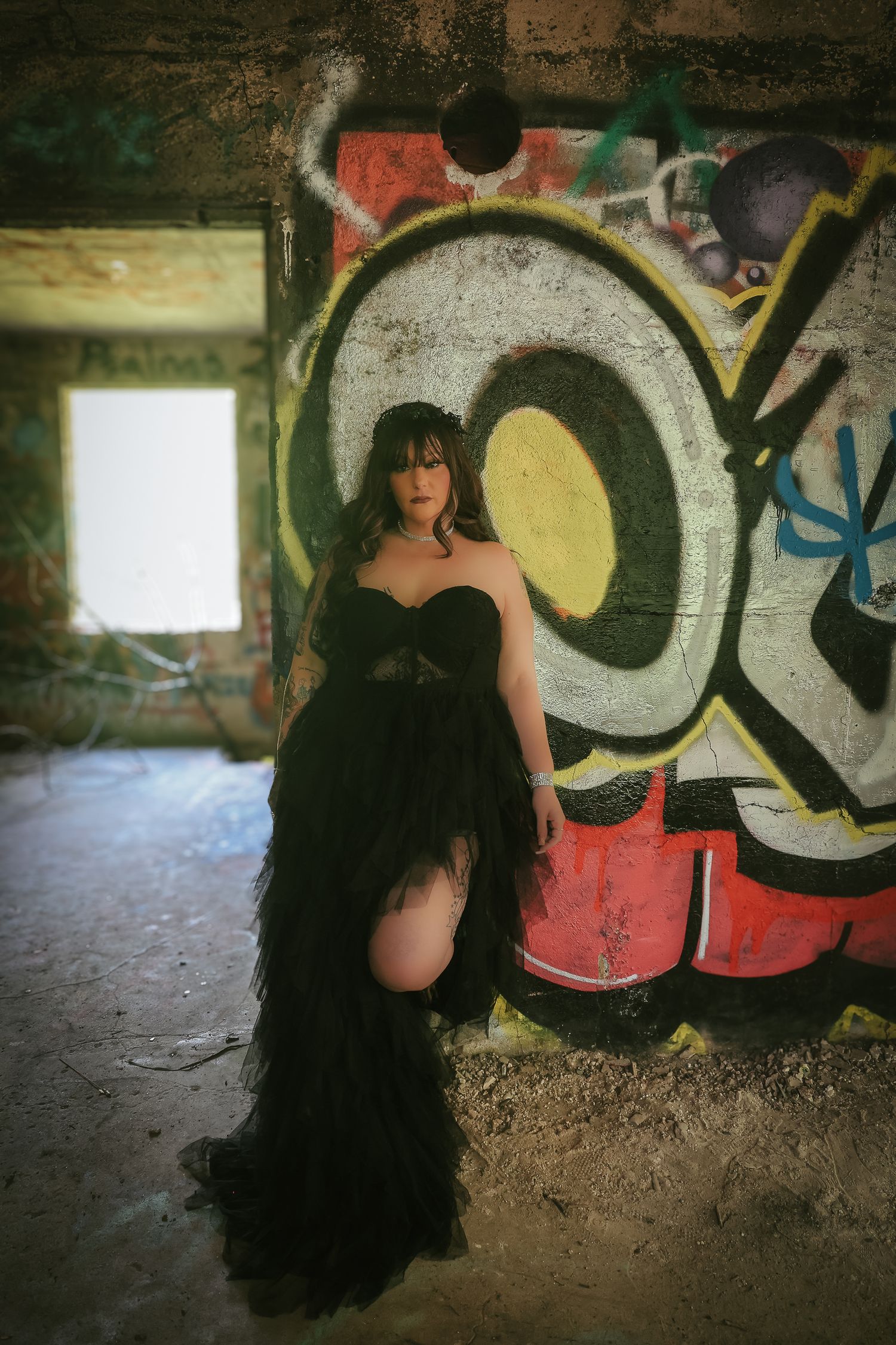A figure in dark clothing crouches against a graffiti-covered wall in a series of sequential artistic photographs.