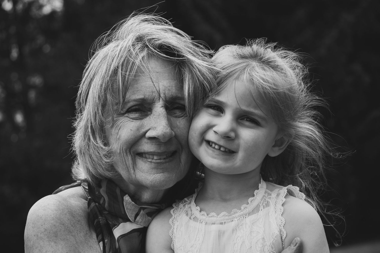 A heartwarming black and white portrait of two people sharing a joyful moment together outdoors.