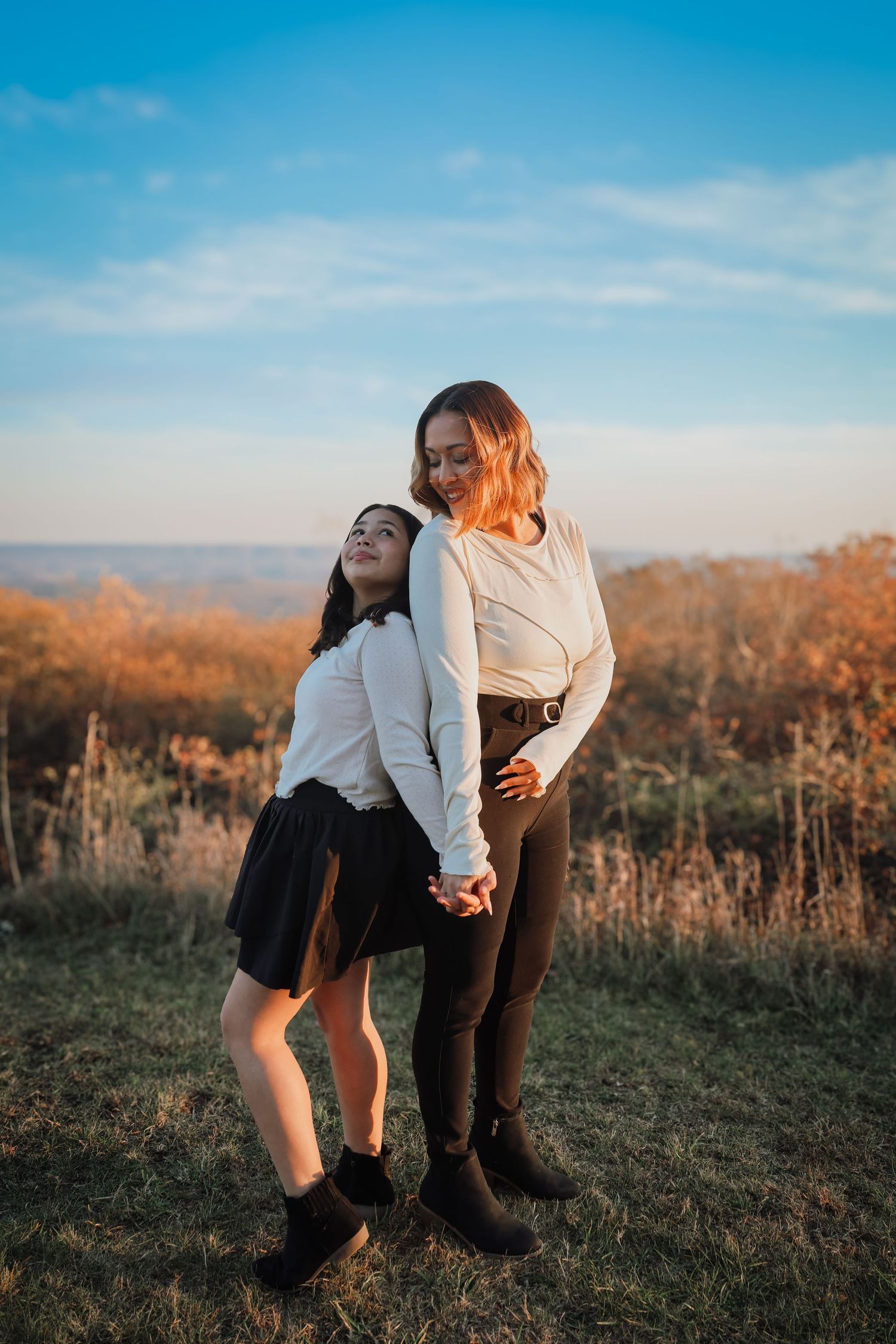 A couple shares a tender moment in a field during golden hour as sunlight illuminates the autumn landscape.