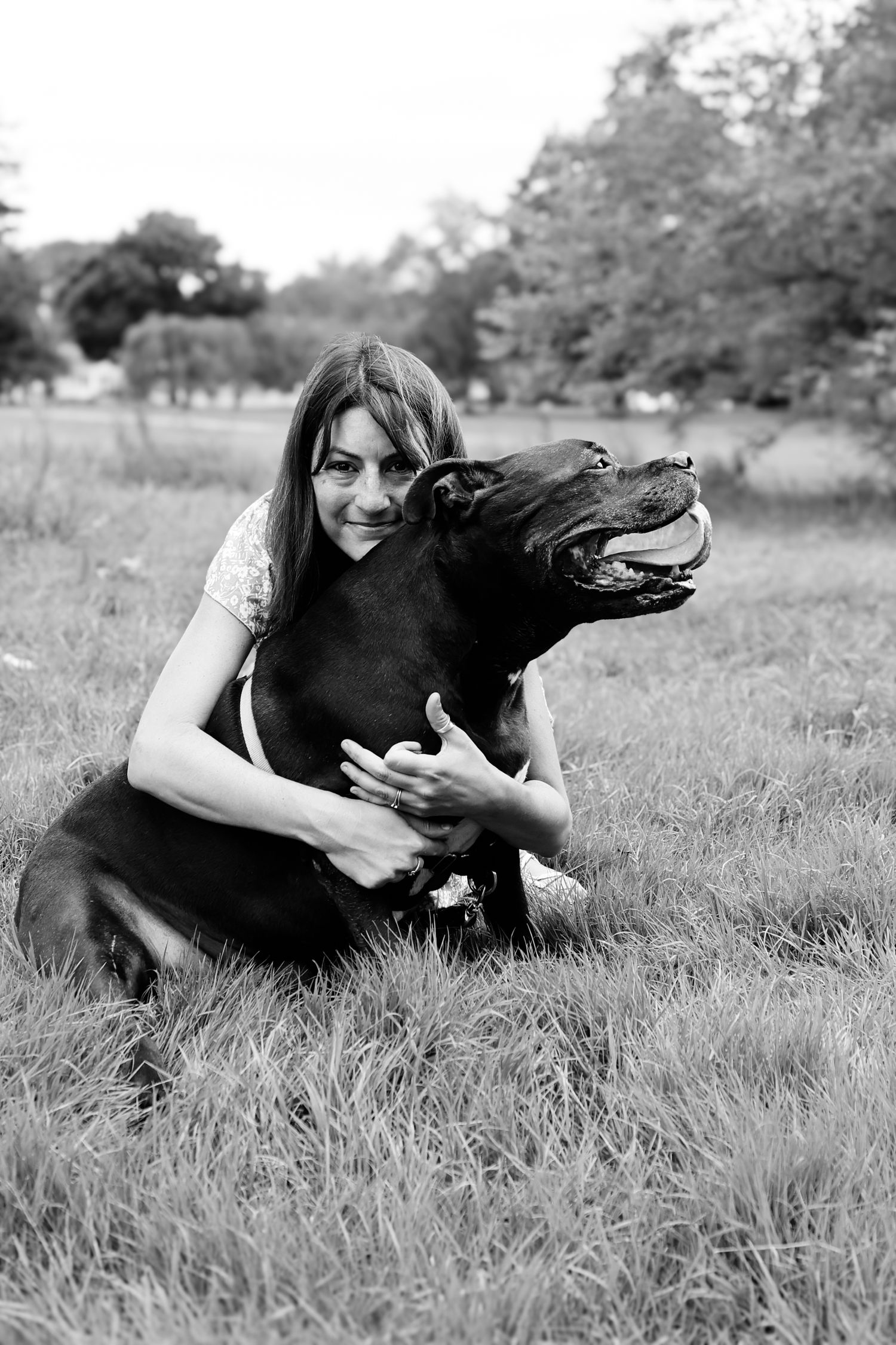 Black and white photo series showing a person and their black dog lying together in a grassy field.