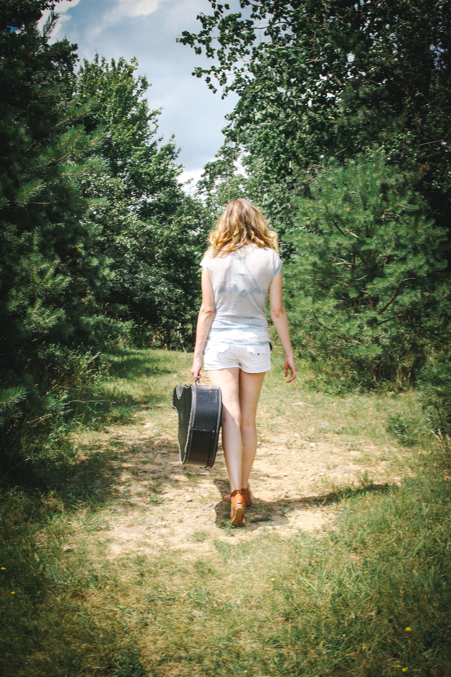 A sequence of photos showing someone walking along a dirt path through an orchard carrying a basket on a sunny day.