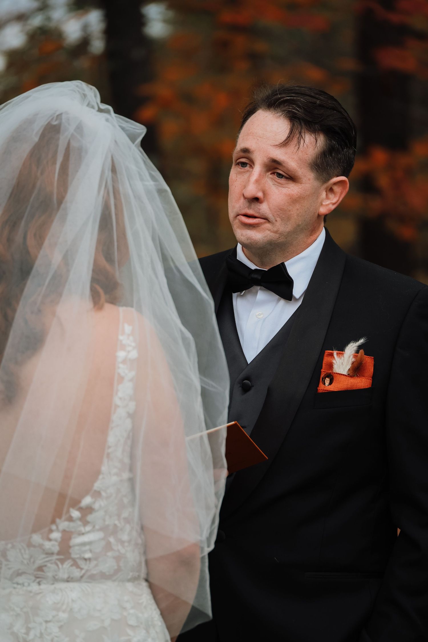 Bride and groom share an intimate moment during autumn wedding with bride wearing delicate lace veil.