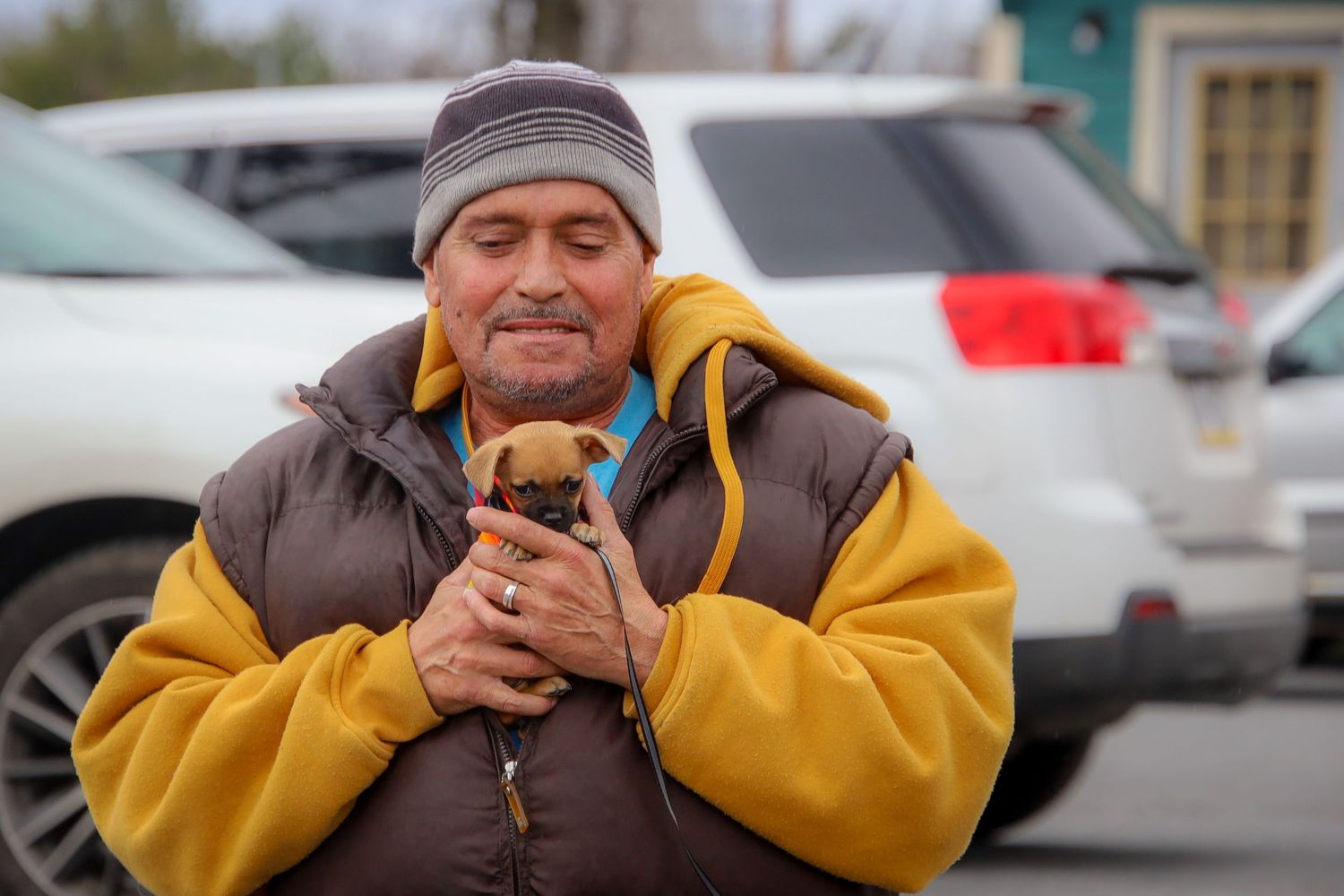 Person in yellow jacket and gray beanie enjoying a hot beverage outdoors on a cold day.