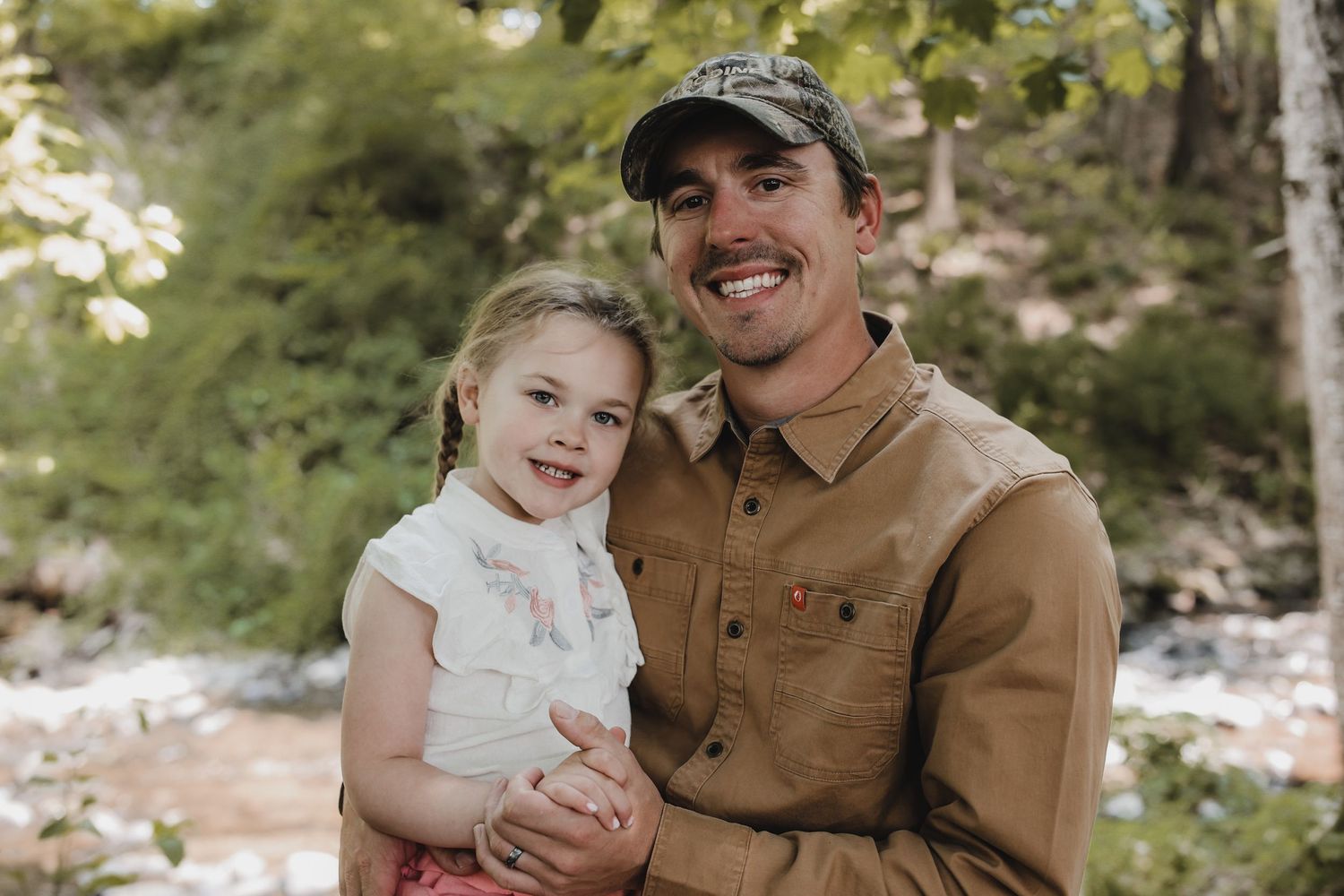 Parent and child share a tender moment outdoors in autumn while wearing matching brown clothing.