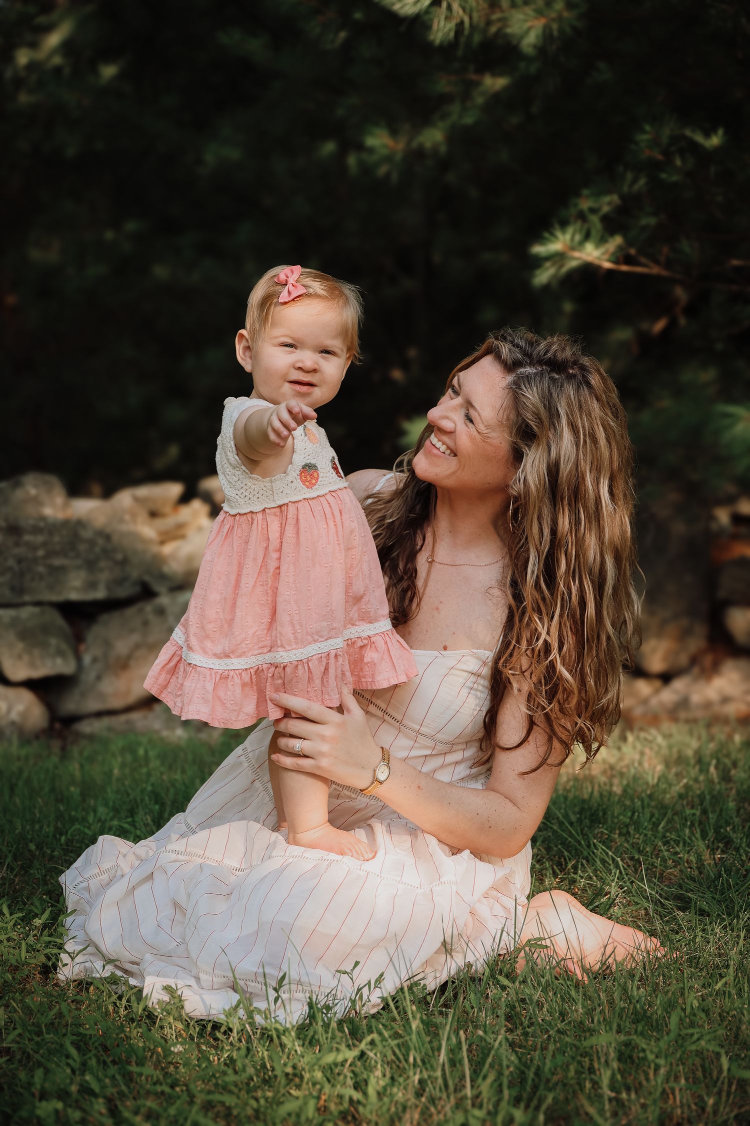 A tender moment captured in a garden setting with soft lighting and coordinating pink and white dresses.