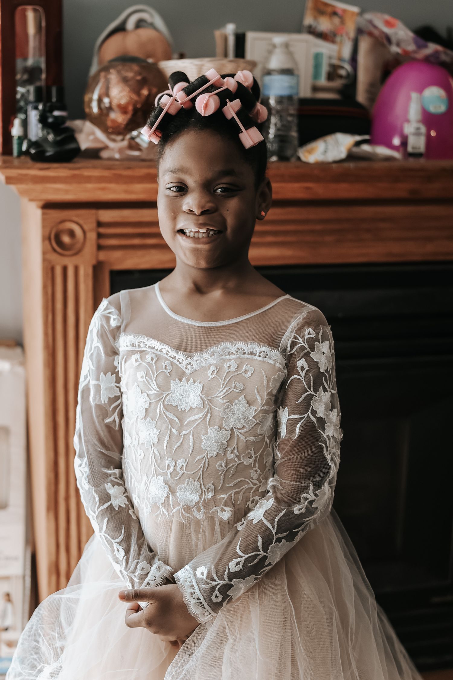 A delicate white lace and tulle flower girl dress with long sheer sleeves and floral embroidery details.