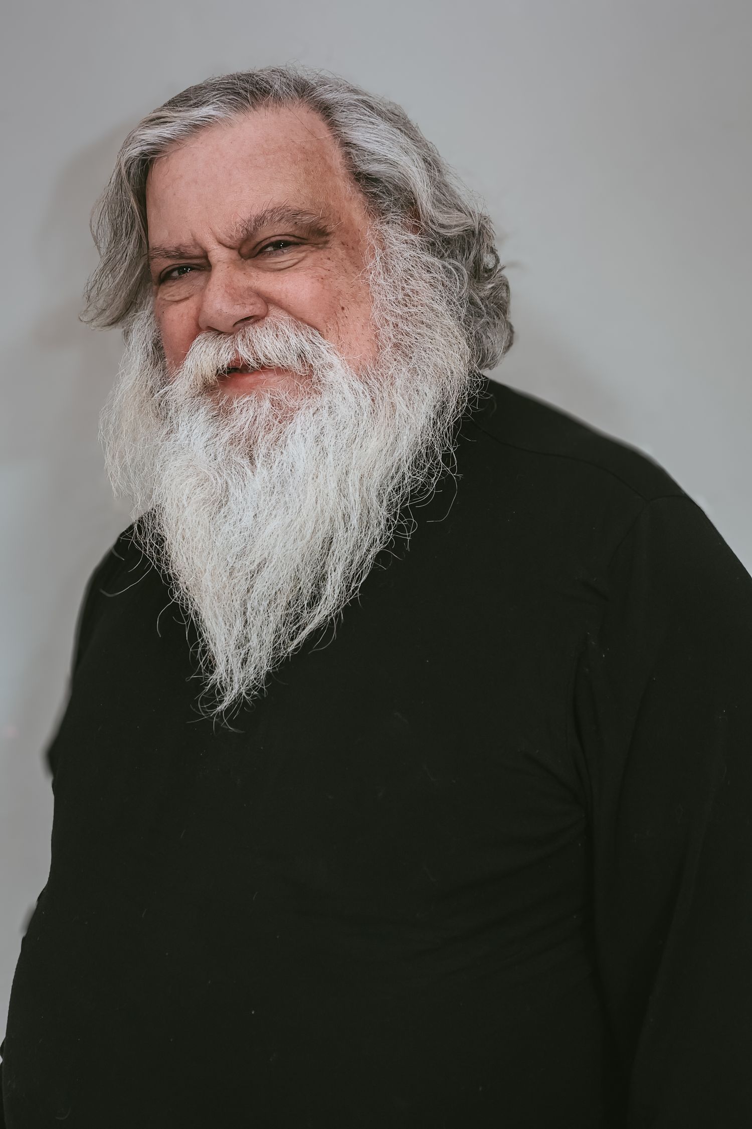 A person with a long white beard is photographed in multiple angles against a gray background.