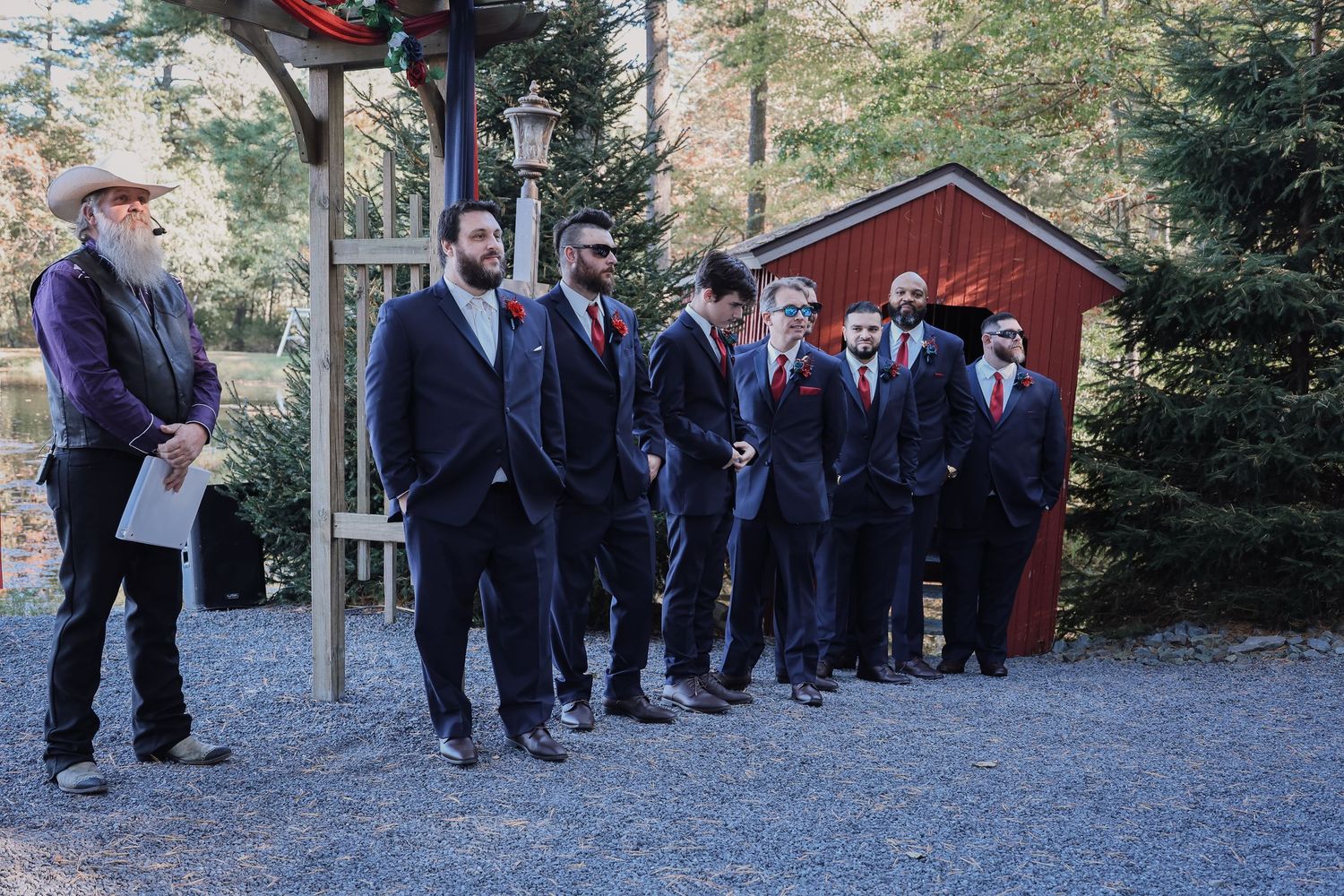 A group of people in formal attire walk along a stone path through an outdoor garden setting.