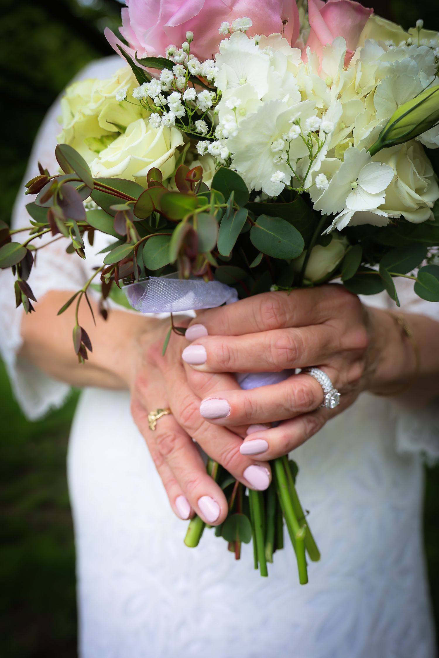 A series of close-up shots showing hands holding a delicate white and pink wedding bouquet with greenery accents.