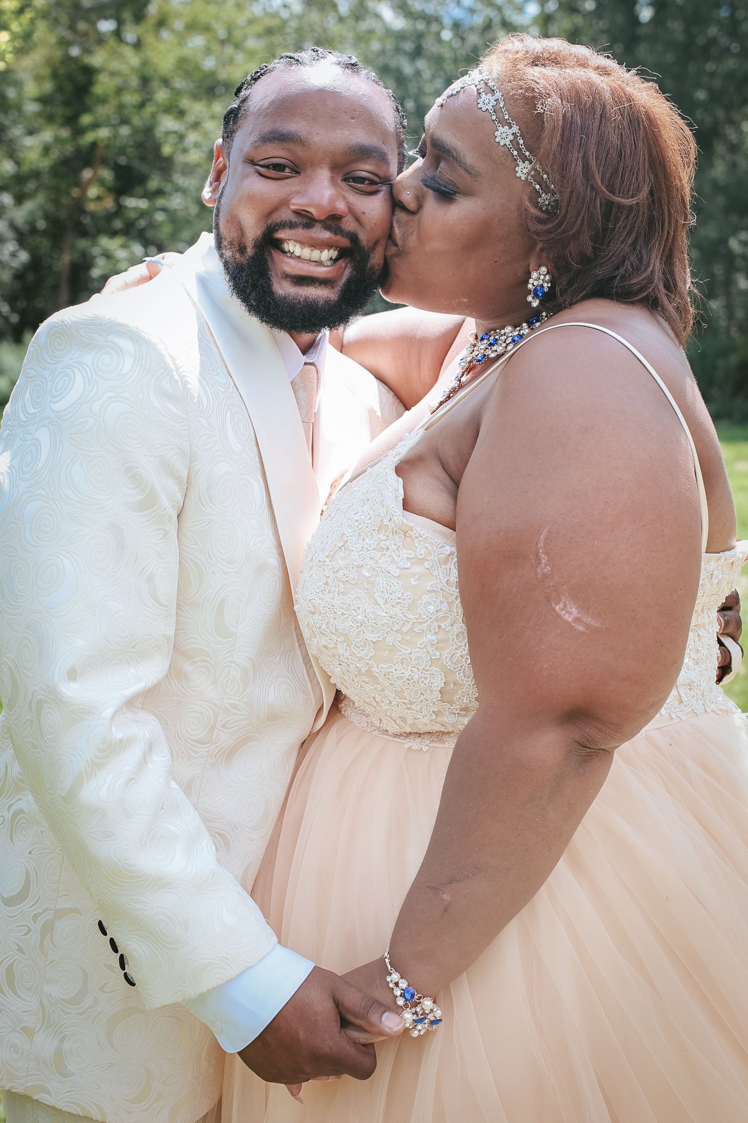 A joyful couple shares a tender moment in their wedding attire, with the bride wearing a sparkly peach gown.