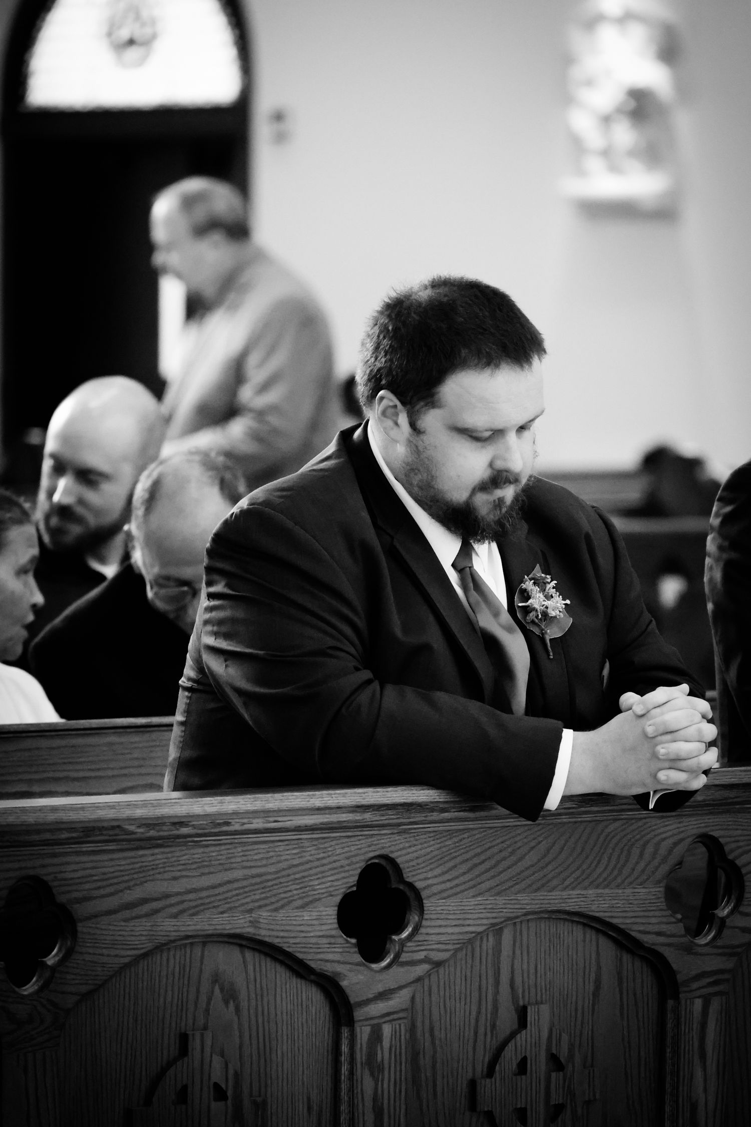 Black and white photo series showing someone in a suit praying while sitting in a church pew during a service.