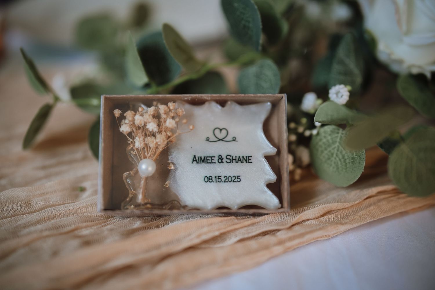Elegant wedding table setting with rustic decor, name cards, and delicate greenery on wooden surface.