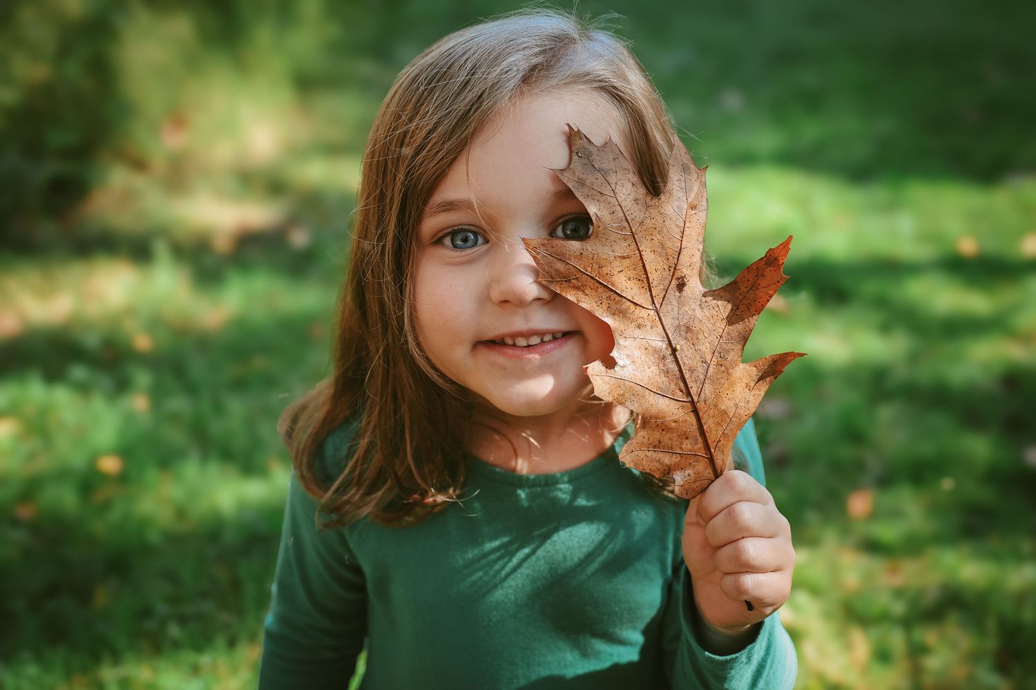 A sequence of images shows someone playfully hiding behind autumn leaves in a green outdoor setting.