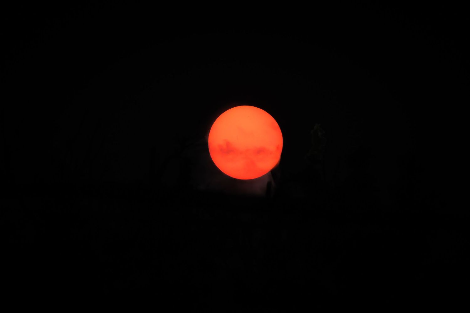 Multiple photos showing the sun as a glowing red-orange orb against a dark sky in different phases and positions.