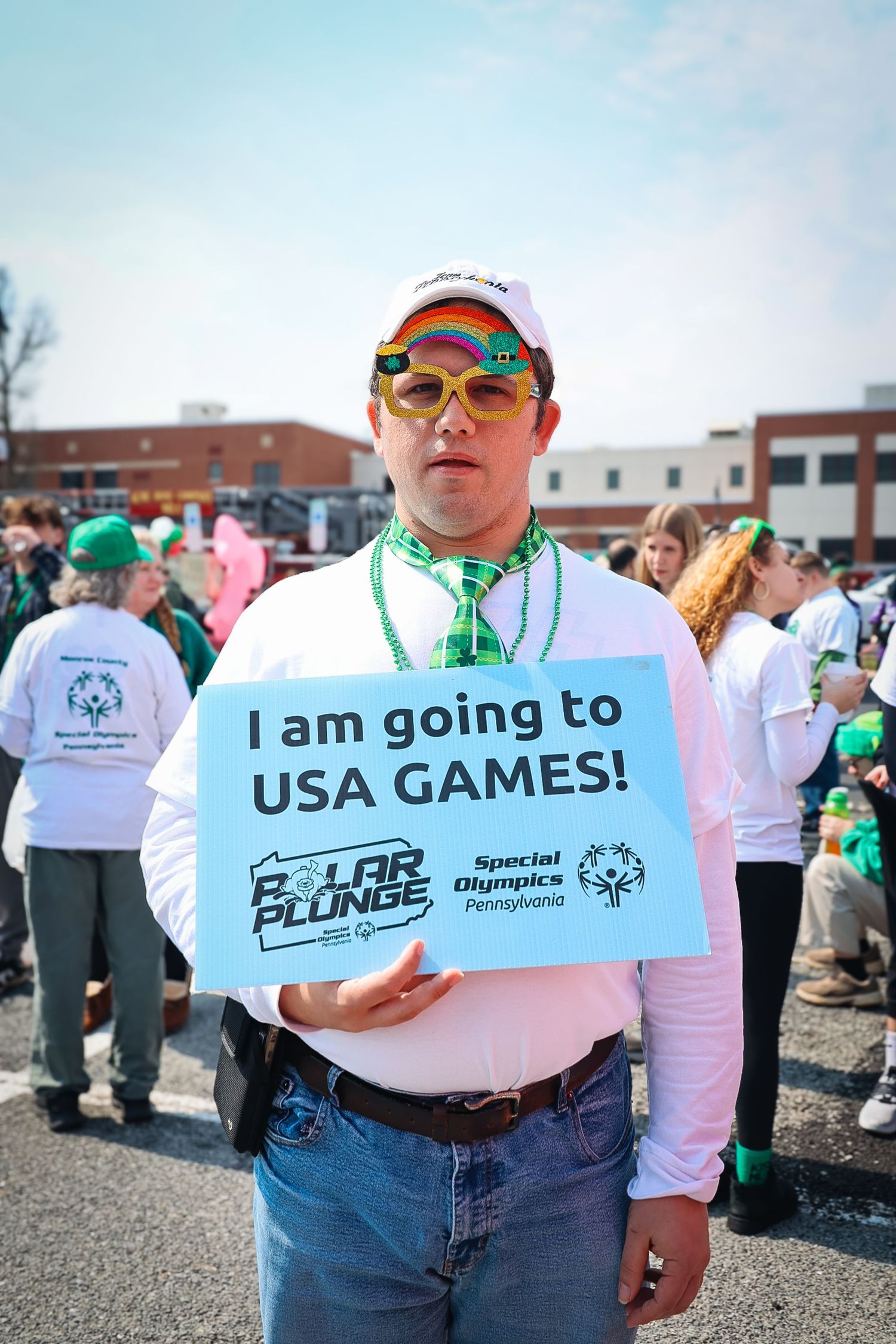 Man holding Special Olympics Pennsylvania Polar Plunge sign reading I am going to USA Games at outdoor event.
