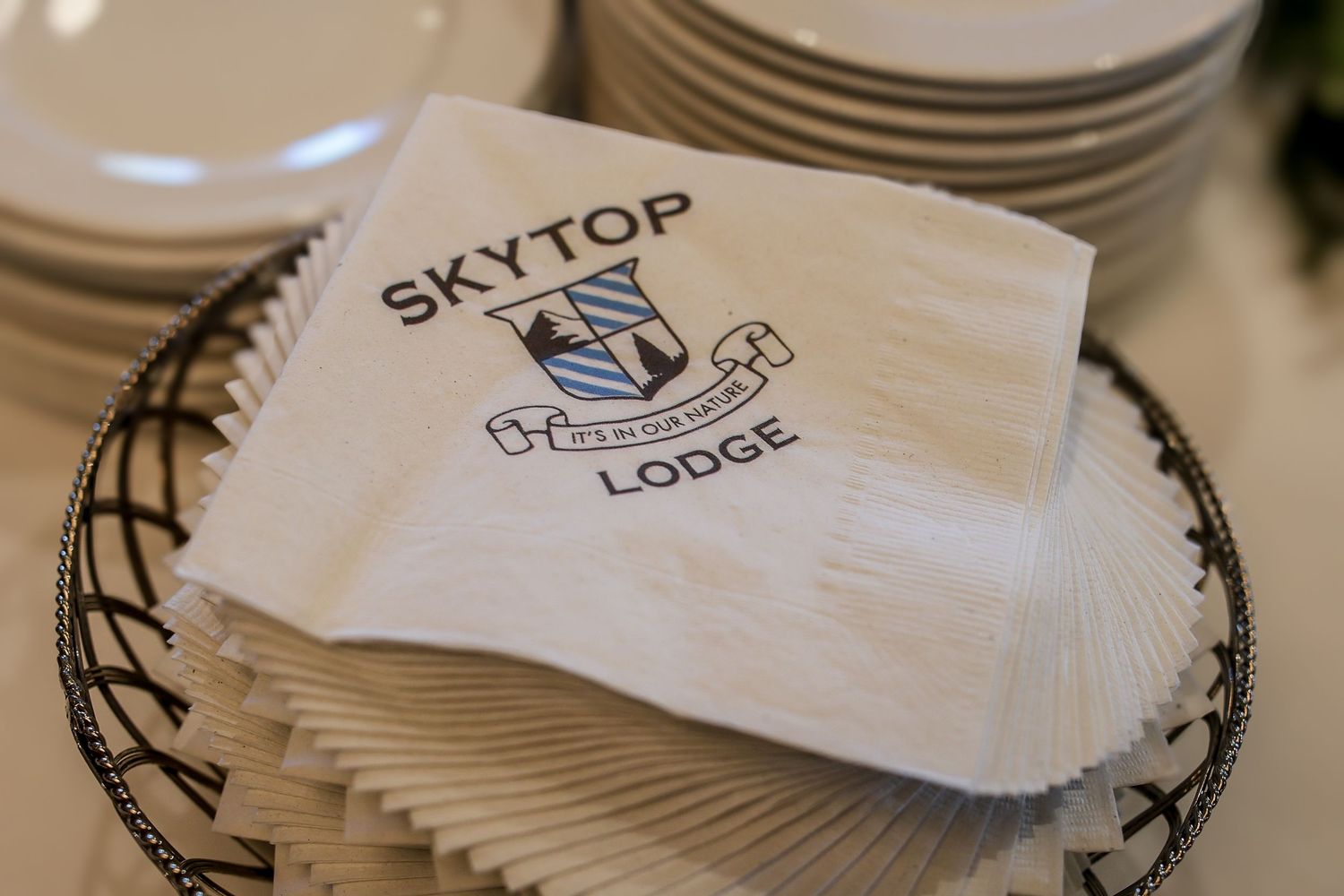 White napkins with Skytop Lodge logo and text stacked on a decorative plate.