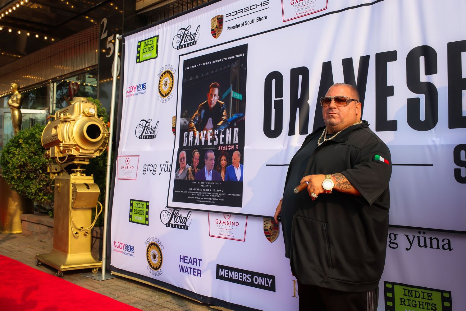 Event attendees gather in front of a backdrop with sponsor logos at a media wall during a special occasion.